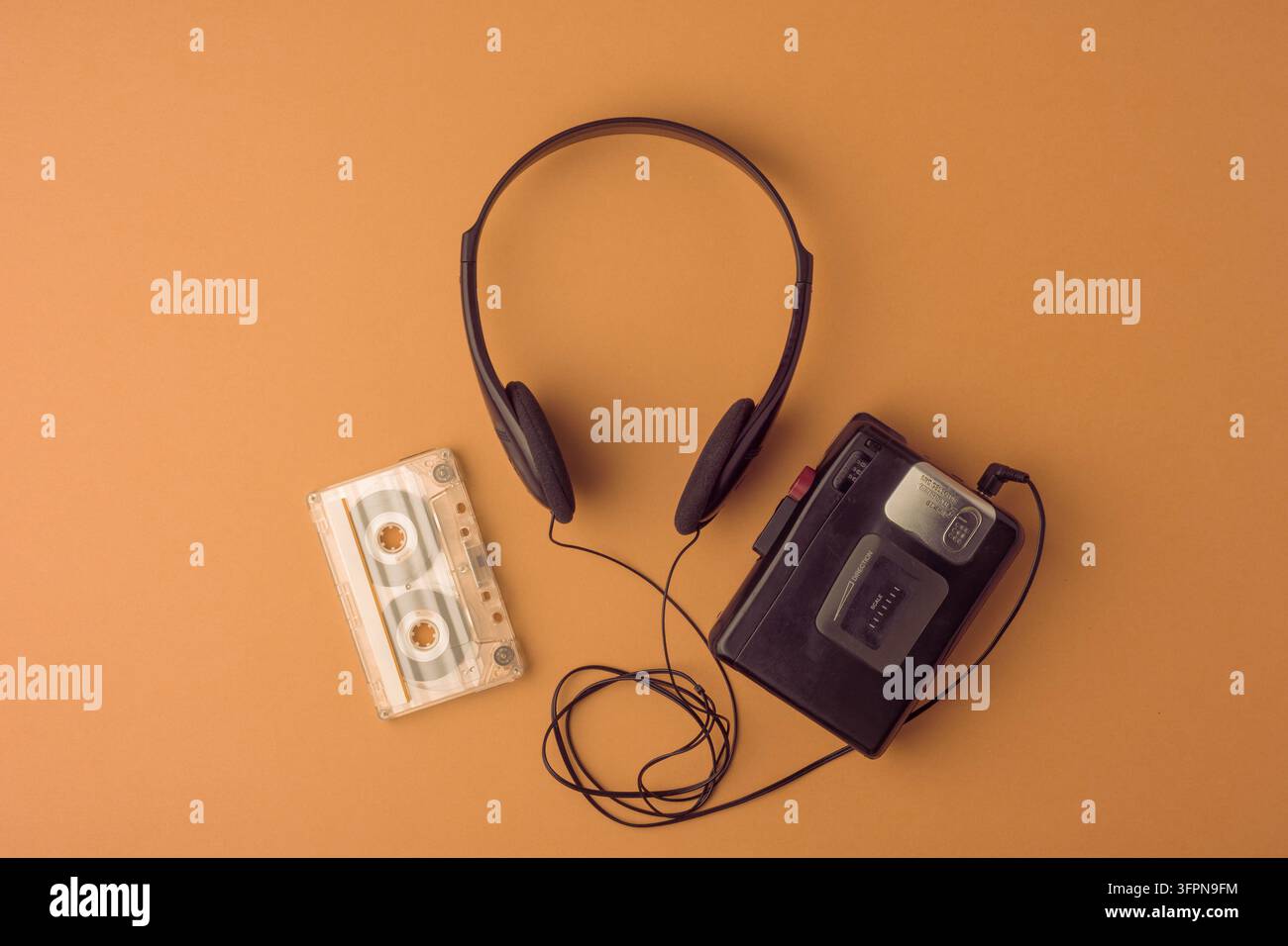Lettore a cassette classico, cuffie e nastro su sfondo marrone risvegliano caldi ricordi degli anni '90. Ampio spazio per la copia per qualsiasi progetto. Foto Stock