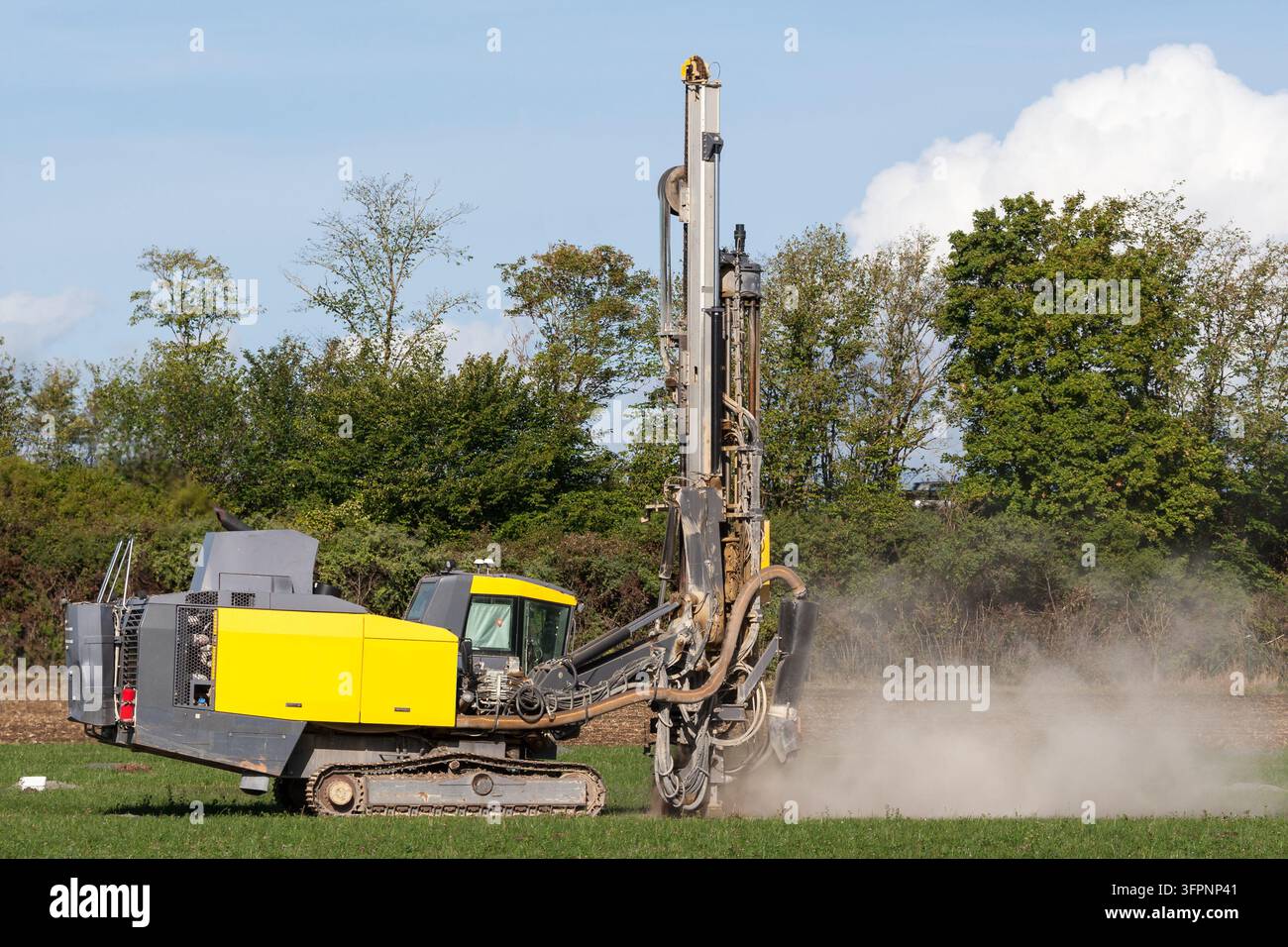 Potenza brutale per l'energia pulita. Una piattaforma di perforazione mobile solleva polvere mentre prepara il campo per il futuro fotovoltaico. Foto Stock