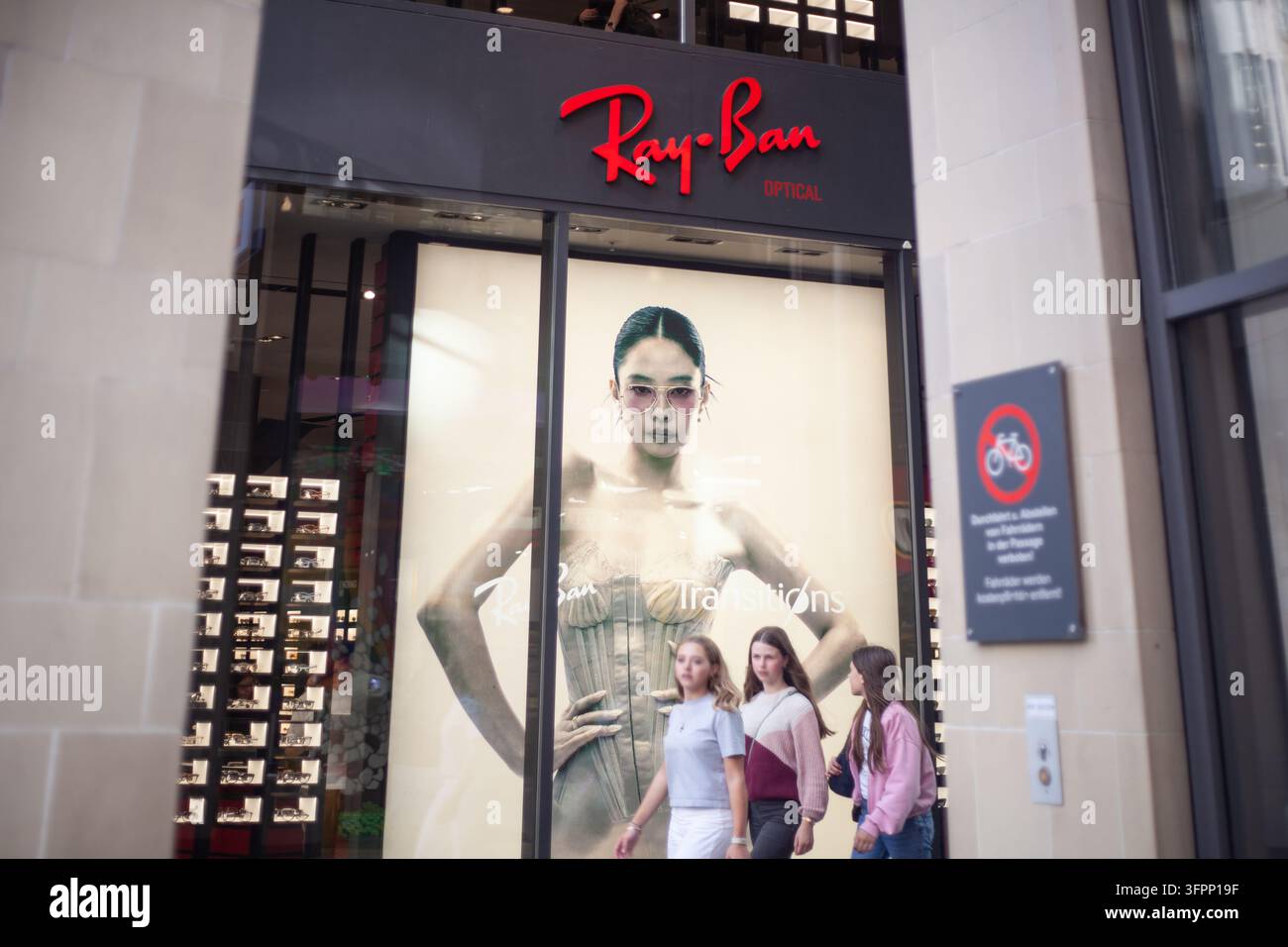 La vetrina luminosa e le lettere del logo aziendale della boutique di occhiali di lusso Ray-Ban nel centro città di Monaco di Baviera, Germania. Foto Stock