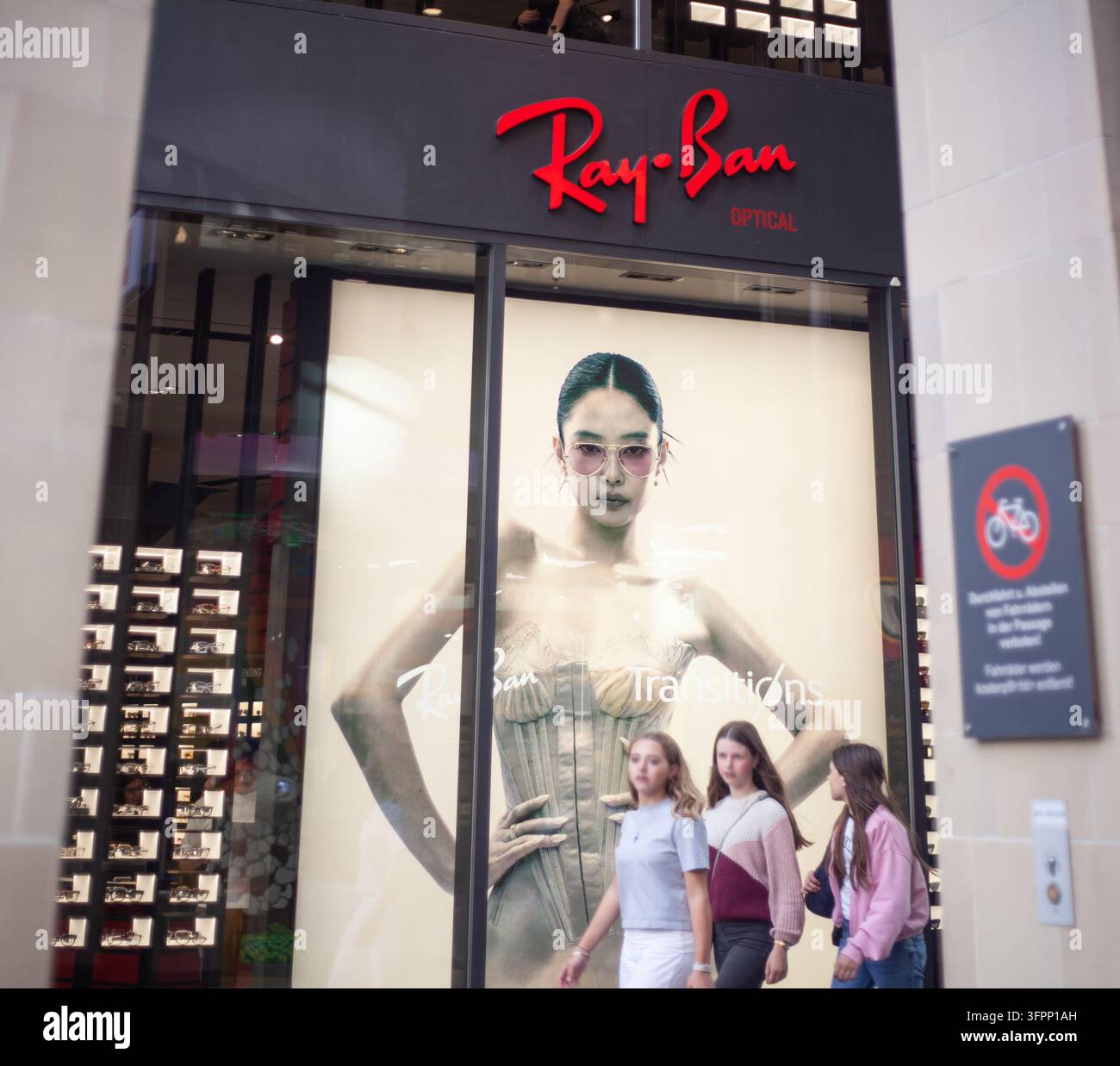 La vetrina luminosa e le lettere del logo aziendale della boutique di occhiali di lusso Ray-Ban nel centro città di Monaco di Baviera, Germania. Foto Stock