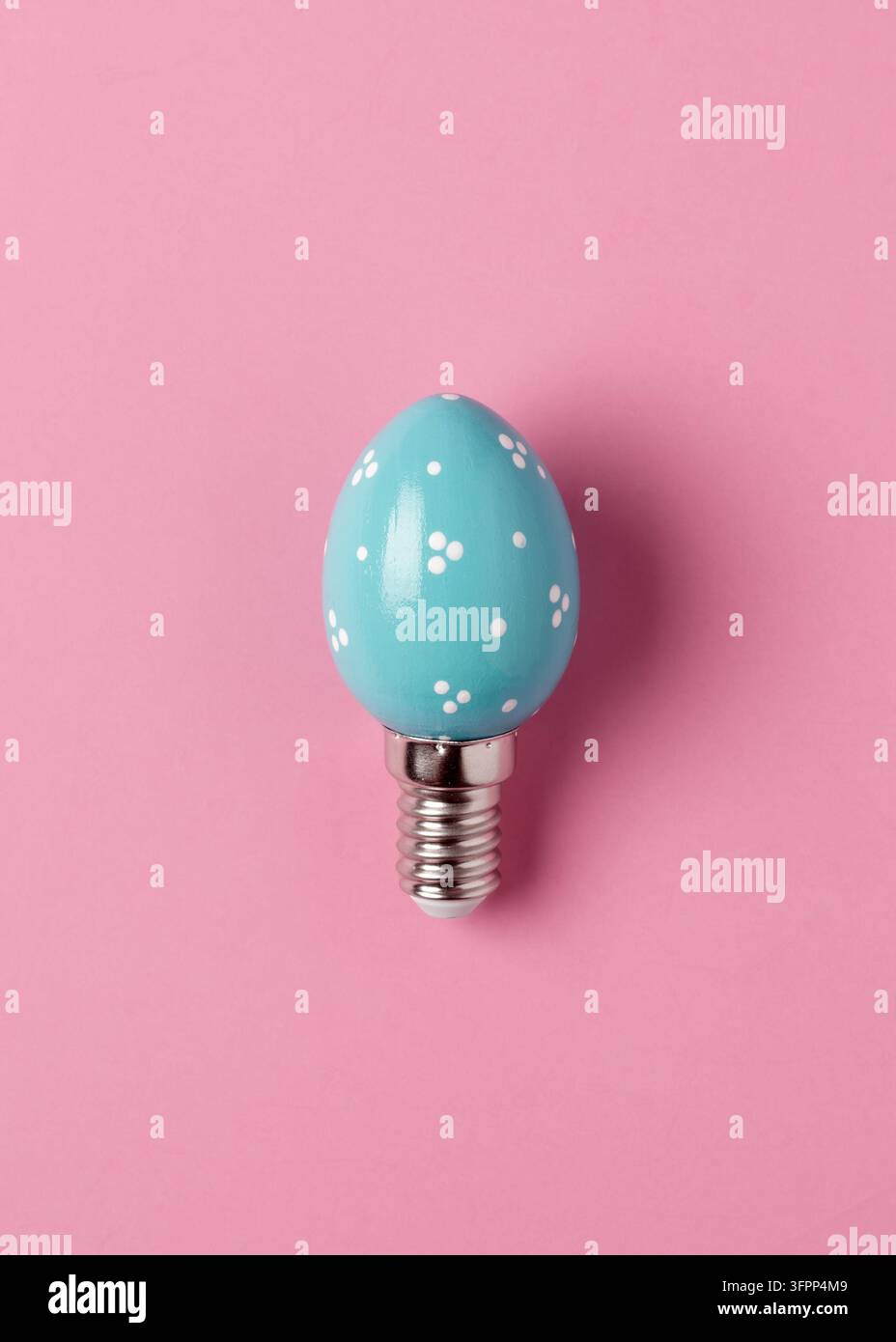 Lampadina turchese a forma di uovo con punti bianchi su sfondo rosa, concetto giocoso di Pasqua per idee creative e spazio per il testo. Foto Stock