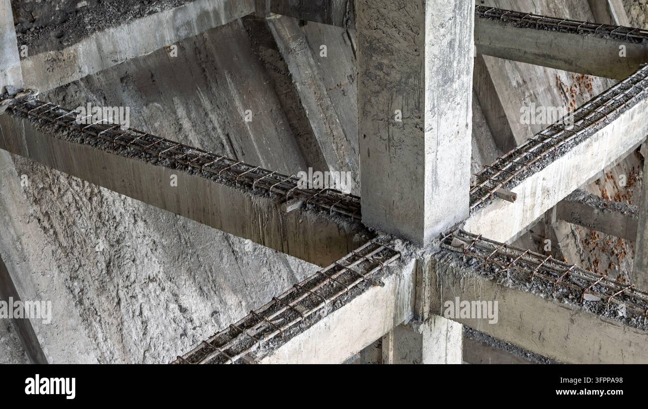 Telaio in cemento armato con rinforzi in acciaio esposti, congelato nel processo di costruzione. Stile industriale brutale con elementi di decadimento. Foto Stock