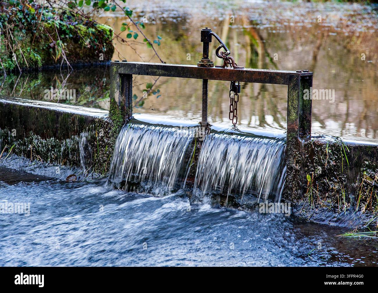 Acqua che scorre attraverso una chiavica fluviale evidenzia l'importanza della gestione dell'acqua e della conservazione ambientale Foto Stock