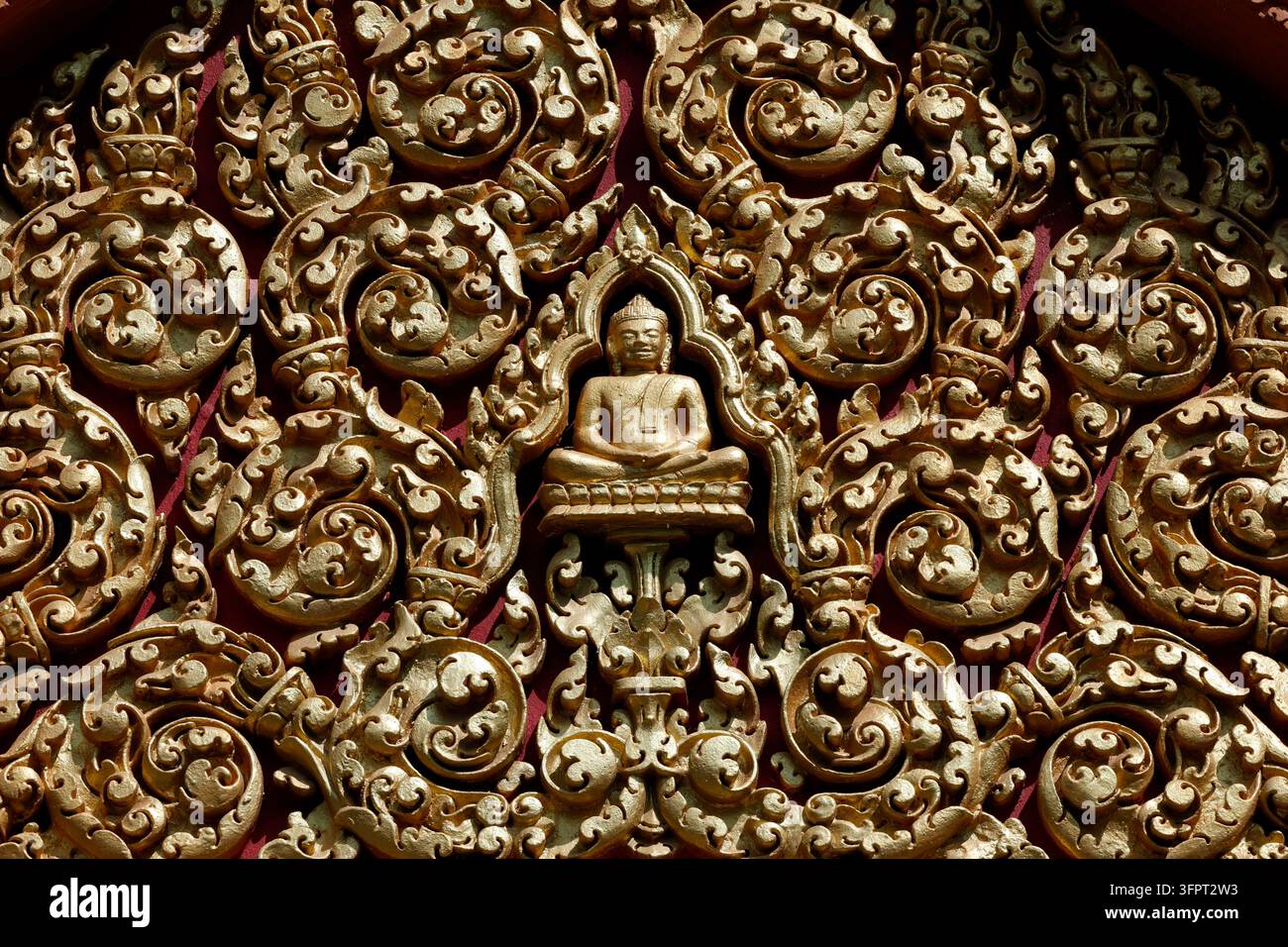 Tempio di Wat Bo. Decorazione in stucco dorato dettagliata in stile Khmer che mostra una figura di Buddha incorniciata da motivi a foglie a spirale. Siem Reap. Cambogia. Foto Stock