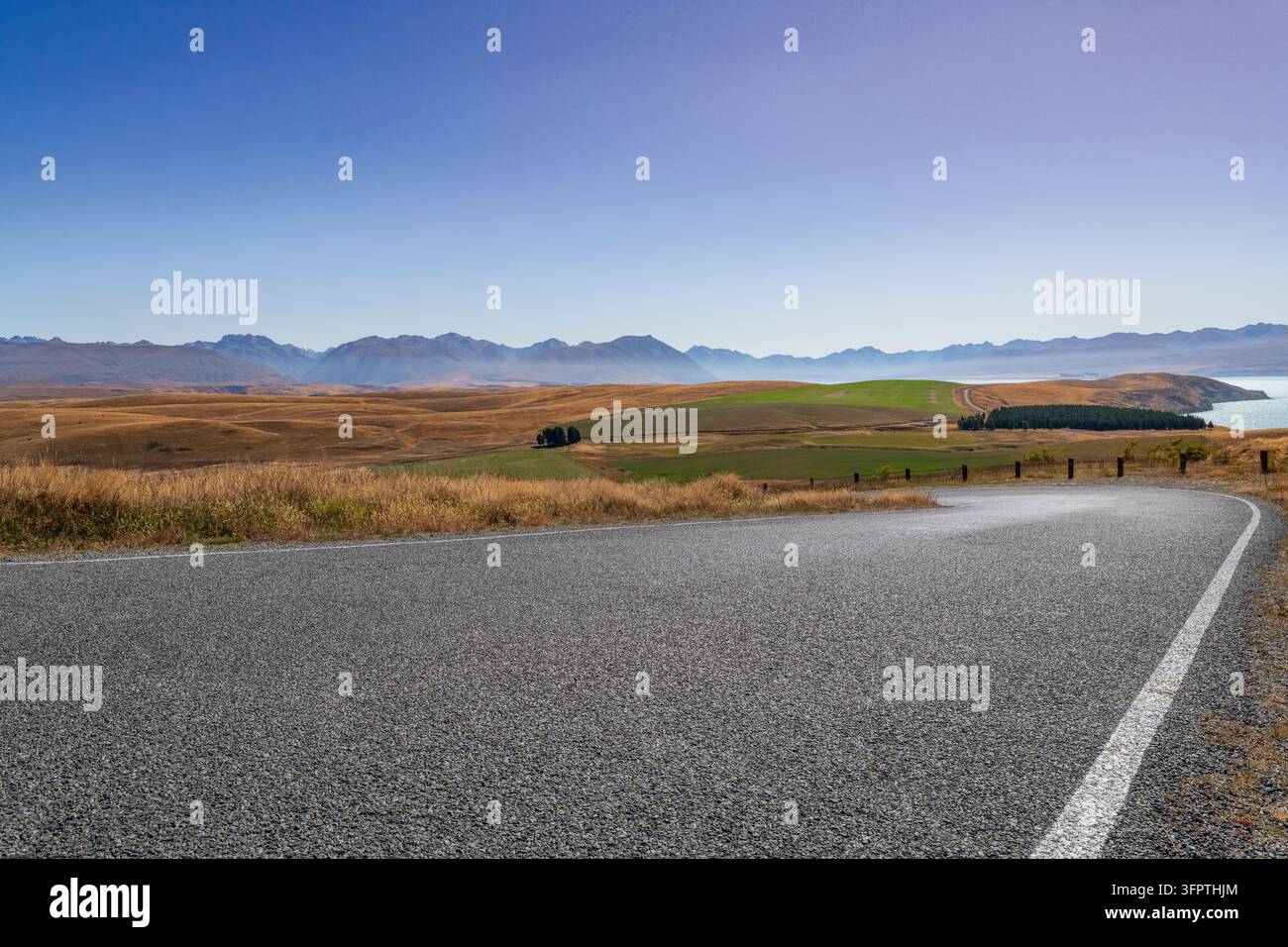 Sfondo stradale, piastra posteriore automobilistica, curva a gomito lastricata in un paesaggio rurale aspirazionale con vedute estese Foto Stock