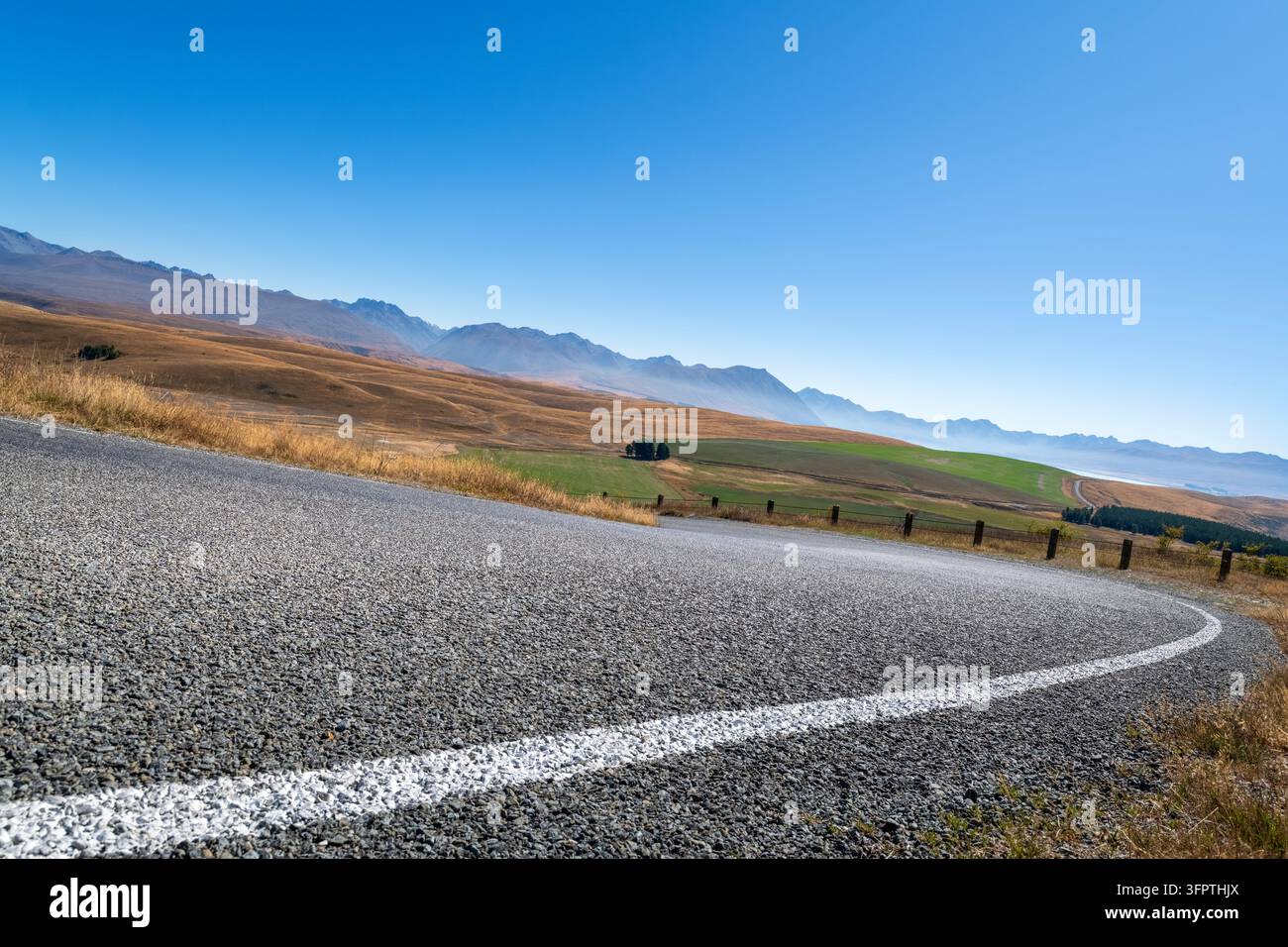 Sfondo stradale, piastra posteriore automobilistica, curva a gomito lastricata in un paesaggio rurale aspirazionale con vedute estese Foto Stock