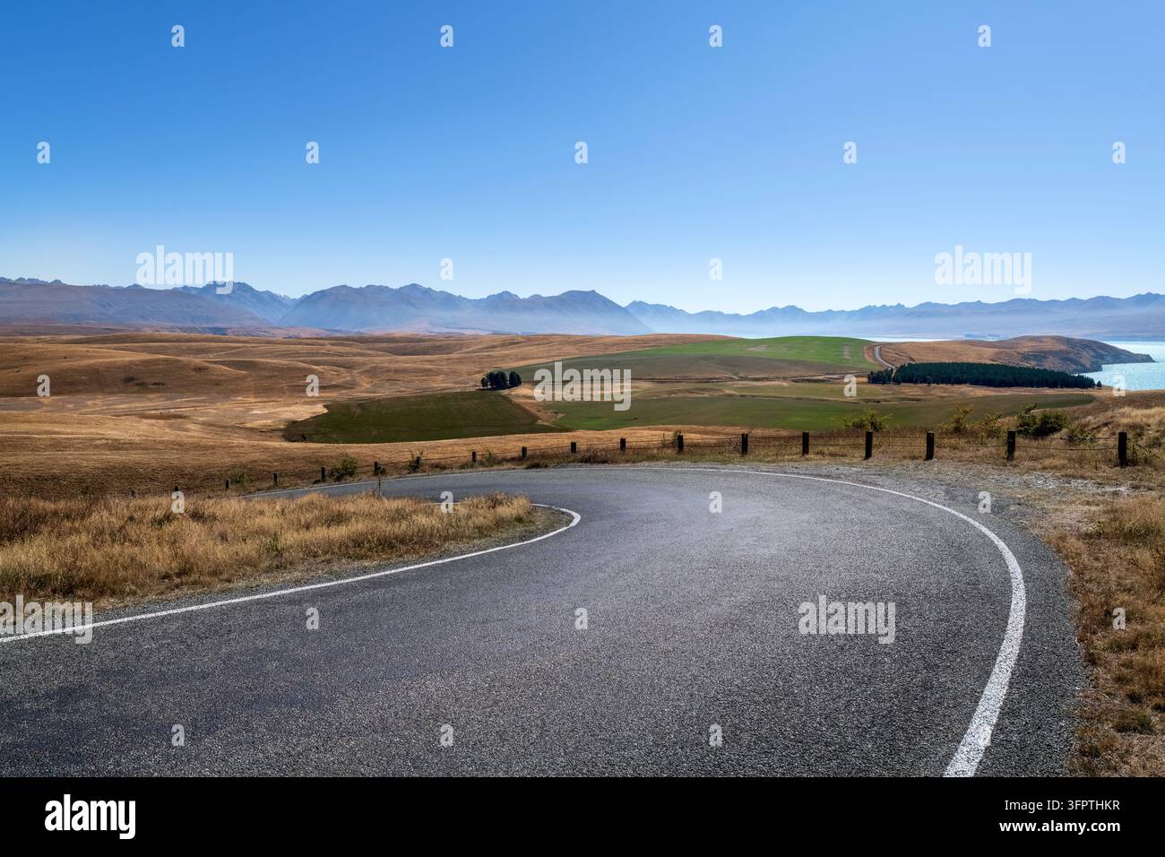 Sfondo stradale, piastra posteriore automobilistica, curva a gomito lastricata in un paesaggio rurale aspirazionale con vedute estese Foto Stock