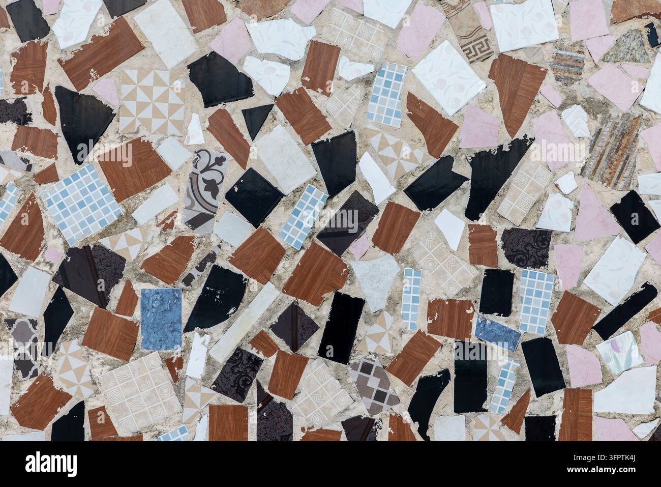 Frammenti di piastrelle di ceramica rotte incastonati nel cemento, muro di pavimentazione crazy riciclato in nero, aspetto legno marrone, frammenti rosa e blu Foto Stock