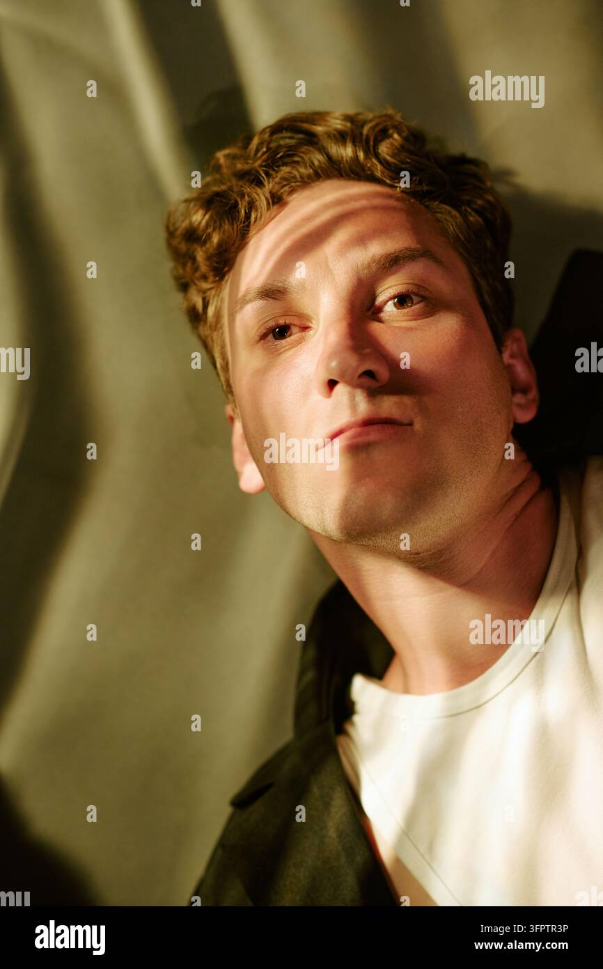 Ritratto di uomo pensieroso che guarda nella fotocamera con ombre drammatiche Foto Stock
