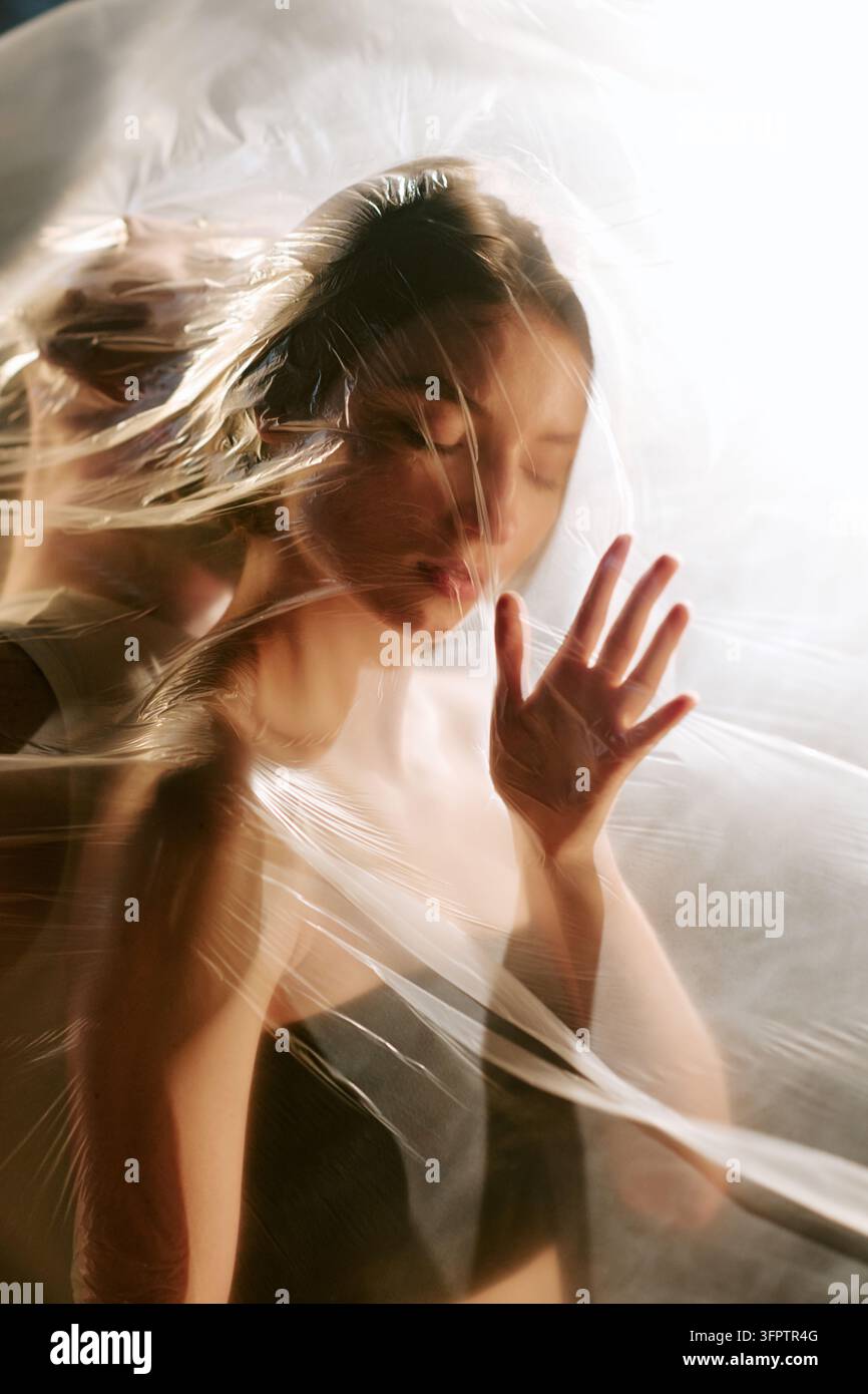 Donna che tocca una pellicola di plastica trasparente che raffigura la soffocazione mentale Foto Stock