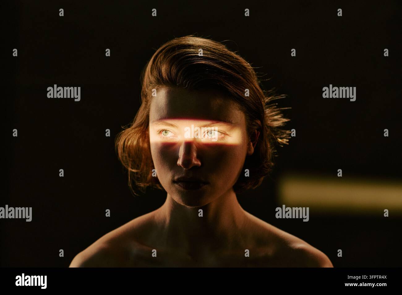 Donna con raggio di luce sugli occhi che posa per un concetto di salute mentale Foto Stock