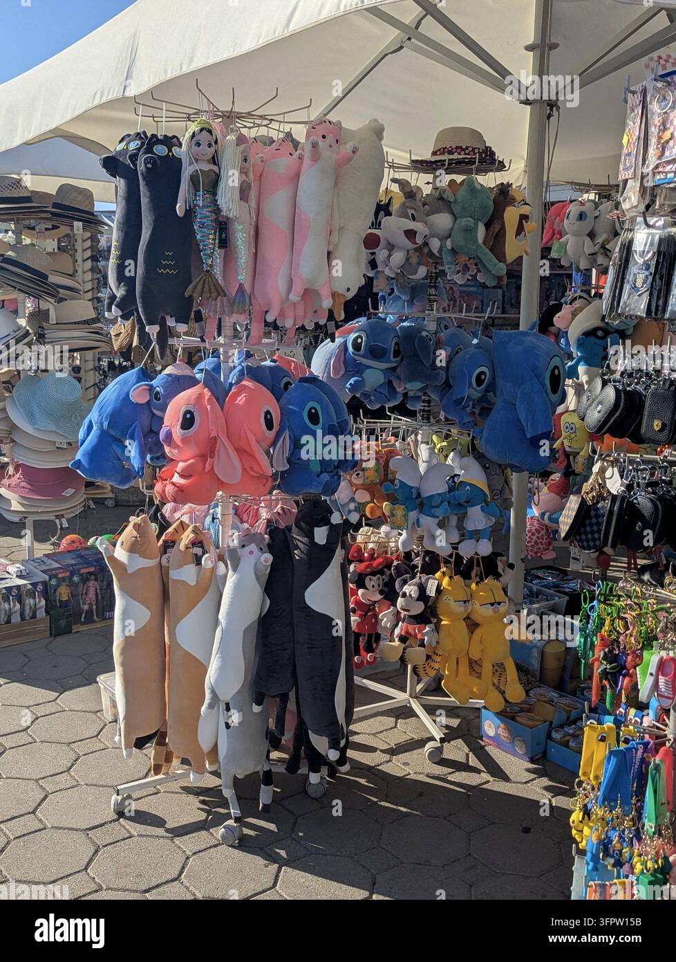Croazia Banco di souvenir all'aperto sotto un tendone bianco che espone peluche colorati, cappelli, portachiavi e piccoli regali disposti su scaffali metallici rotanti Foto Stock