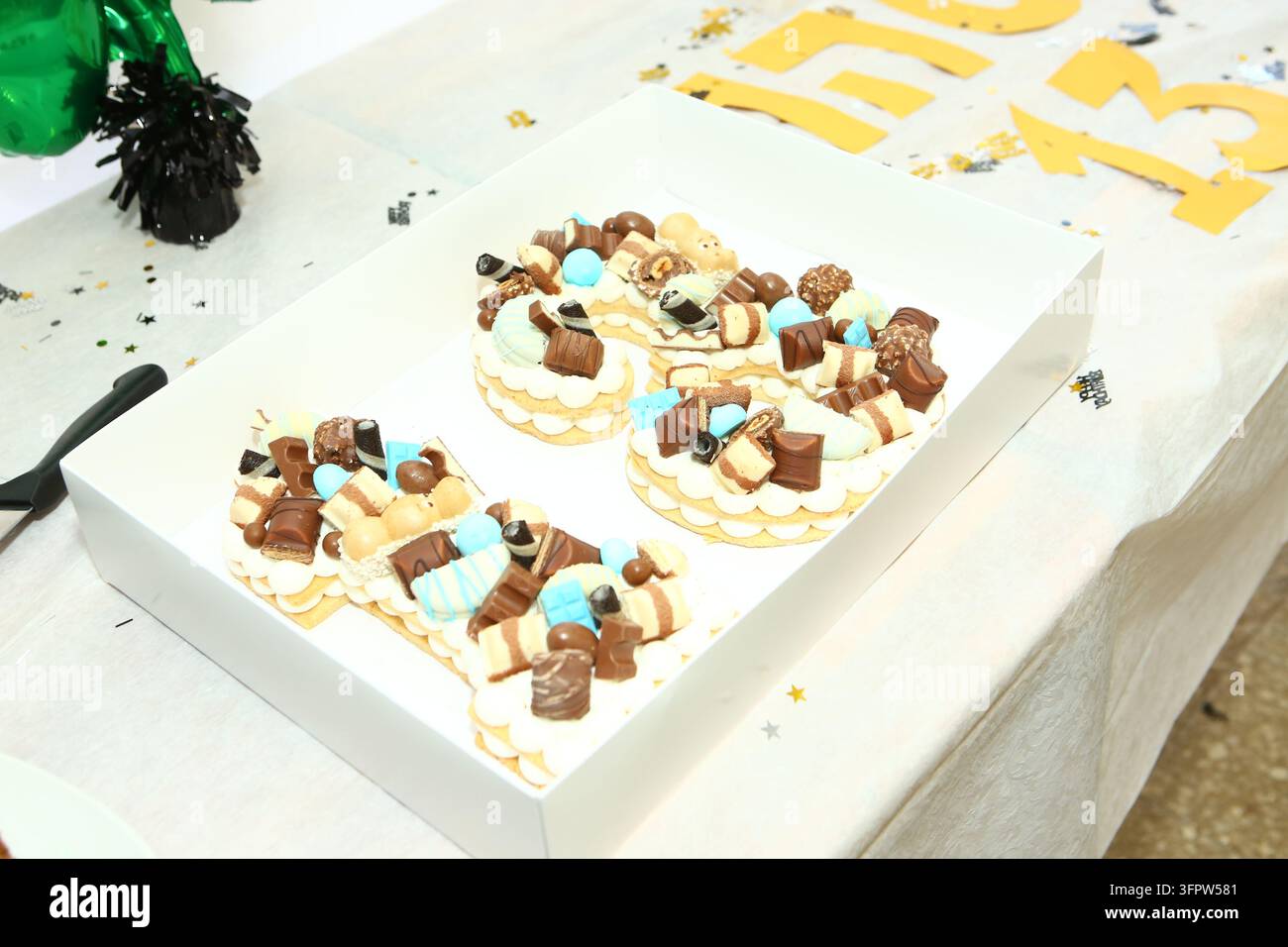 Torta di compleanno a forma di numero decorata con cioccolatini e dolci in una scatola bianca Foto Stock