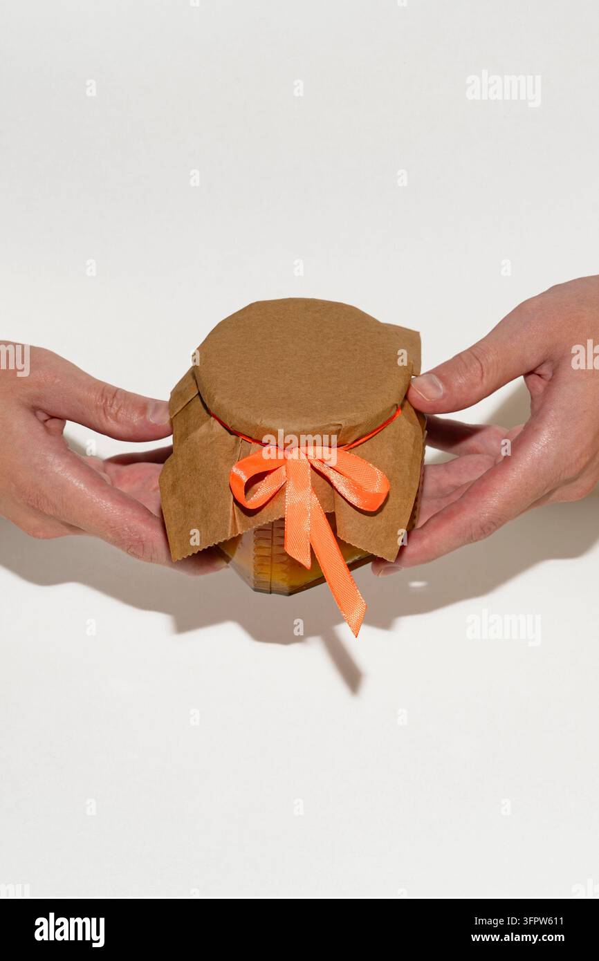 Primo piano di mani che tengono un barattolo di conserve fatto in casa decorato Foto Stock