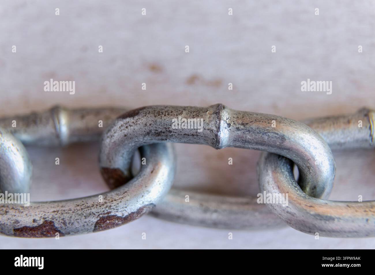 Vista macro di una catena metallica collegata con superfici consumate e arrugginite che evidenziano resistenza, durata e texture industriale. Foto Stock