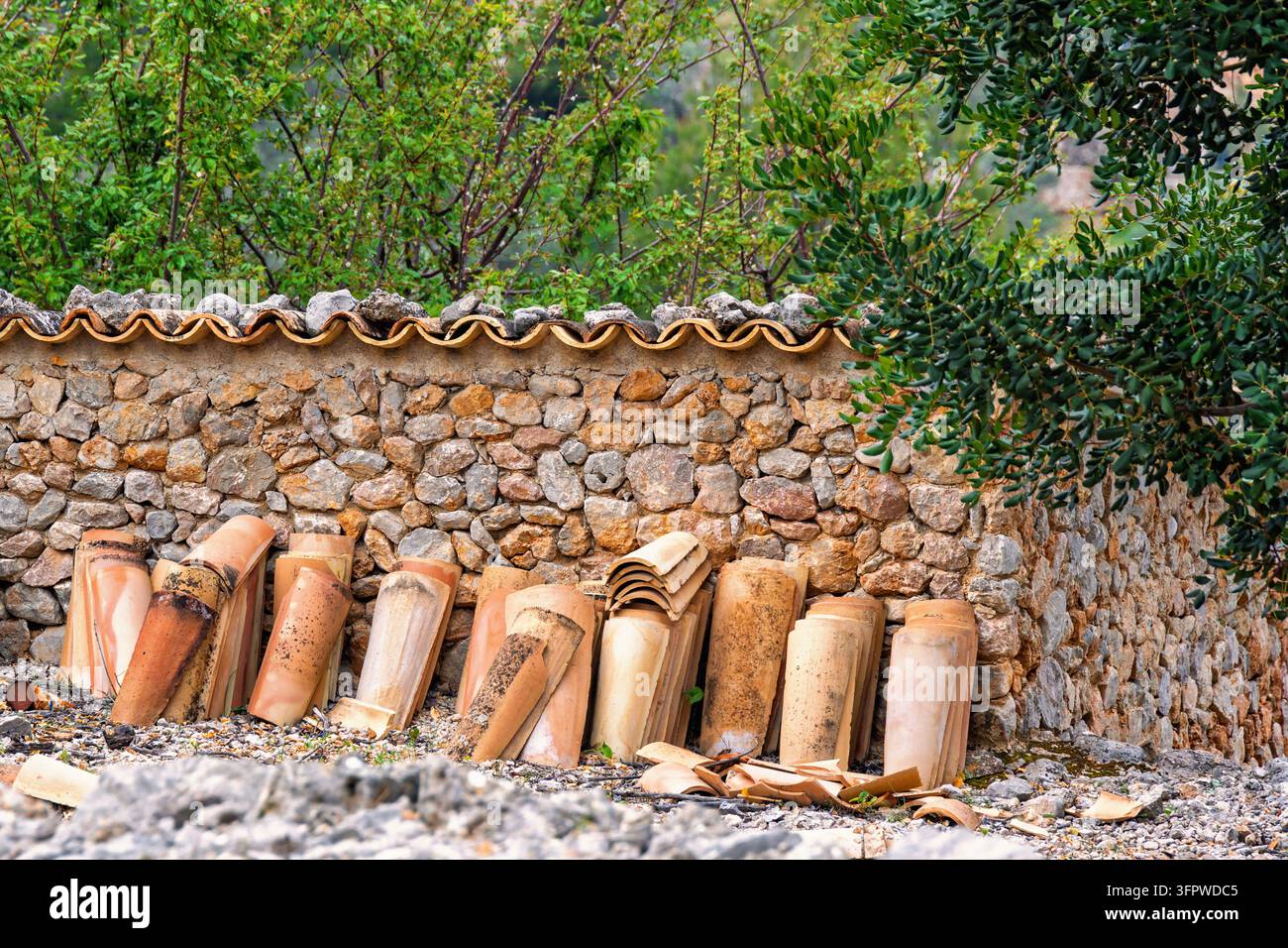 Tegole del tetto vicino a un muro di pietra in un giardino Foto Stock