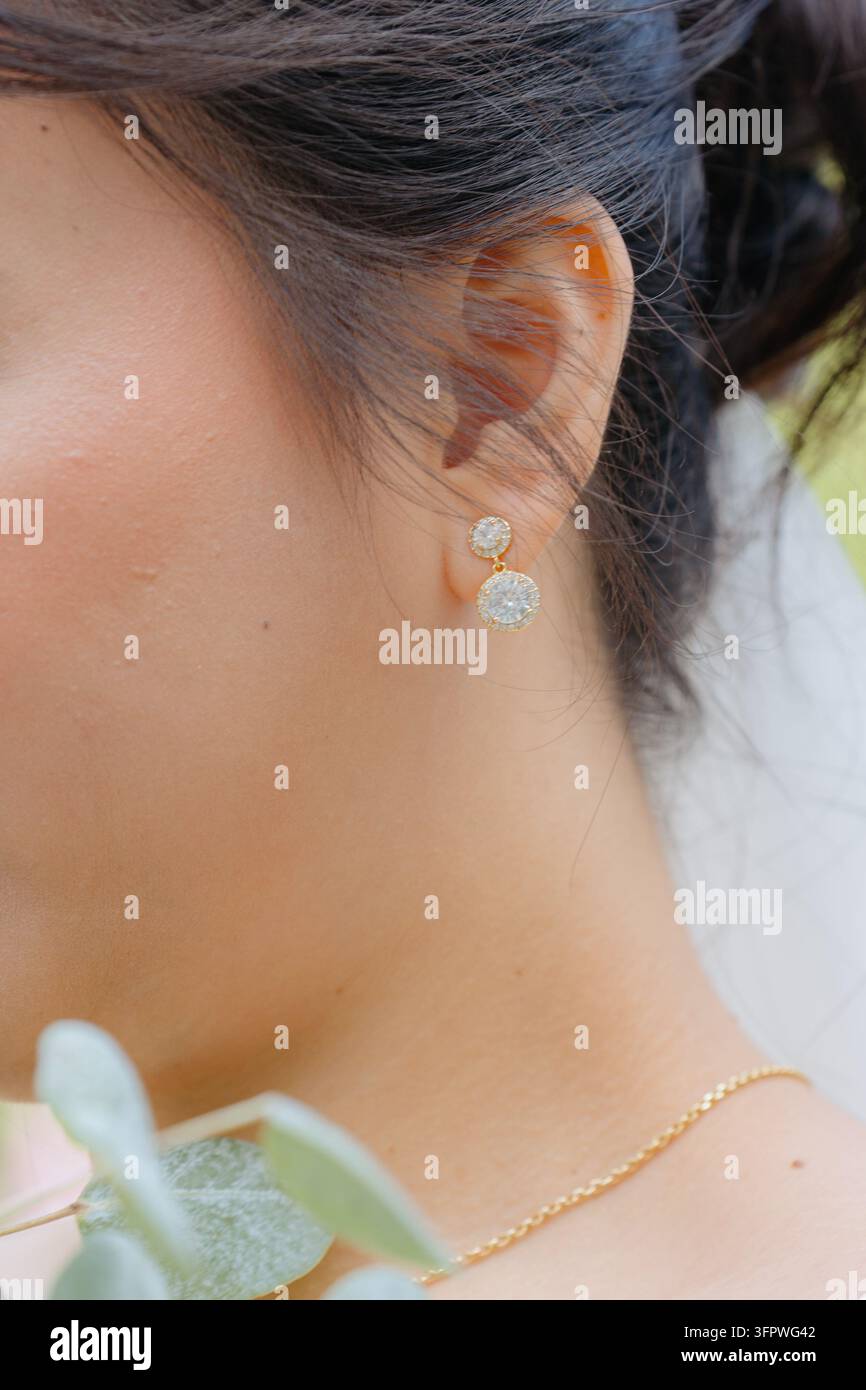 Orecchio con orecchini, all'aperto, con orecchio, orecchini, collana, capelli, da una prospettiva ravvicinata, con accenti dorati e bianchi e un'atmosfera elegante, mostrando Foto Stock