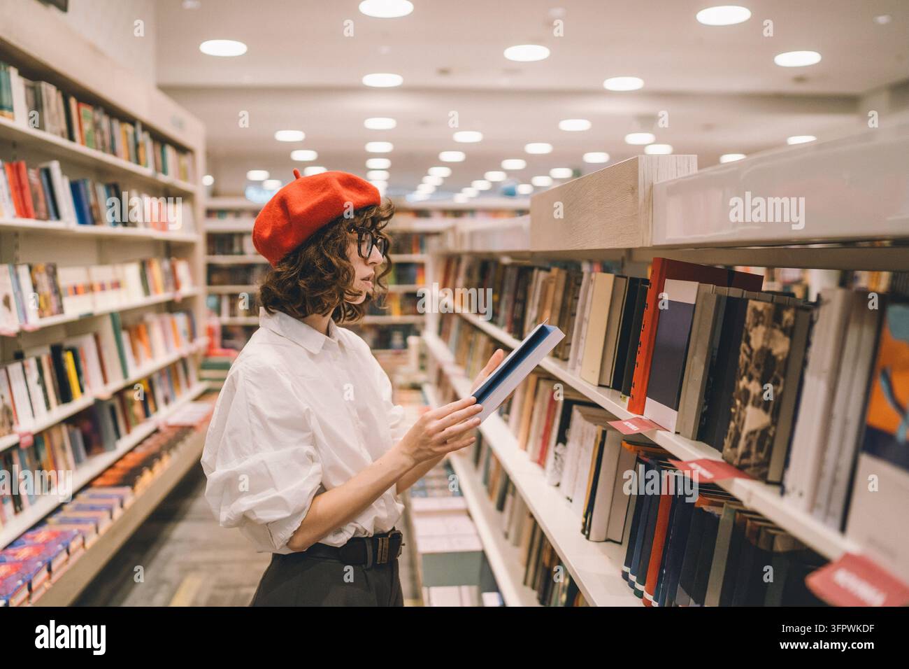 Giovane donna elegante fa acquisti di libri in una libreria moderna Foto Stock