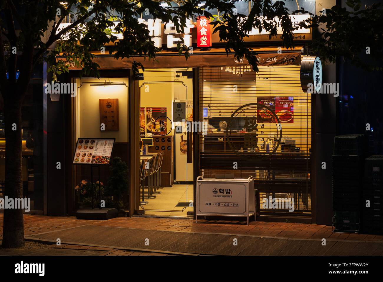 Corea del Sud, Busan – 21 set. 2026: Vetrina illuminata del ristorante coreano Hecbob con cartelli del menu di notte, Haeundae, Busan, Corea del Sud Foto Stock