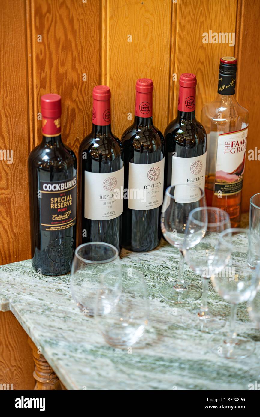 Bottiglie di porto, vino rosso bordolese e whisky scozzese con bicchieri su un mobile di marmo in una tenuta di caccia a Glen Clova, Scozia Foto Stock
