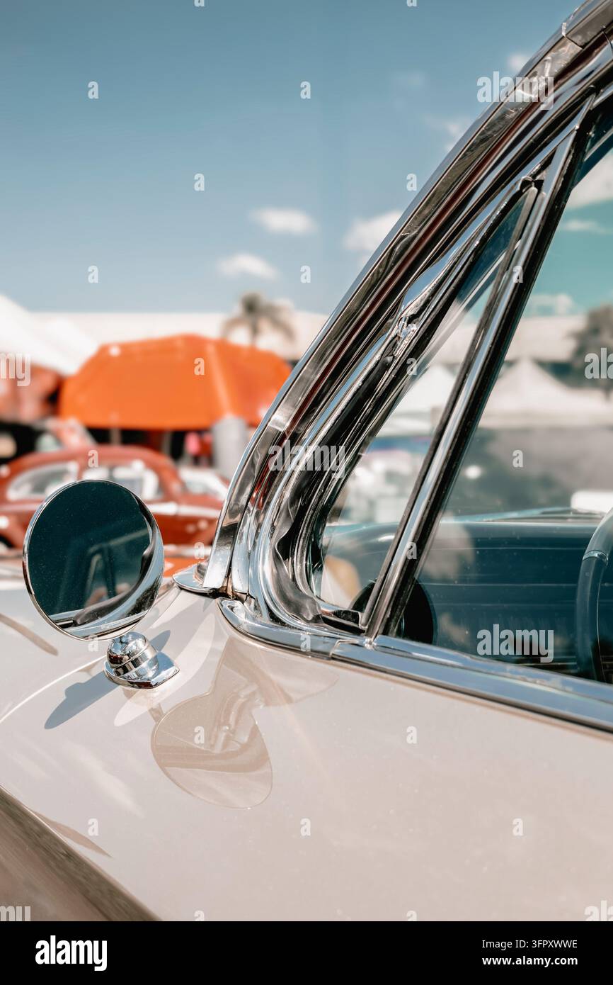 Dettaglio di auto vintage classica con finiture cromate lucide, specchietto laterale e carrozzeria bianca sotto un cielo blu brillante. Foto Stock