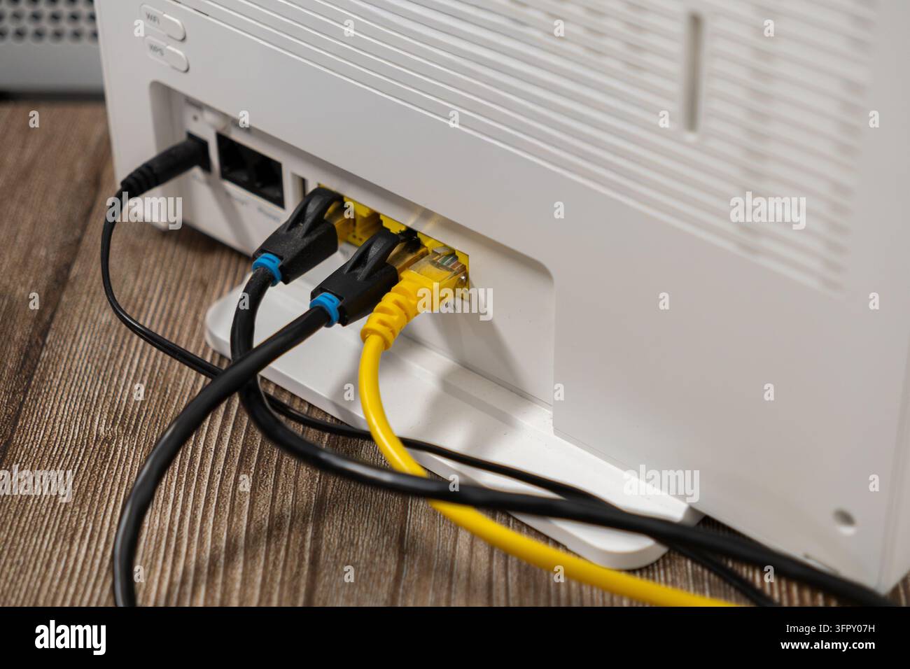 Cavi di rete neri e gialli collegati a un router wireless moderno, rappresentanti una telecomunicazione affidabile, un collegamento digitale, tecnologia di server, ampia Foto Stock