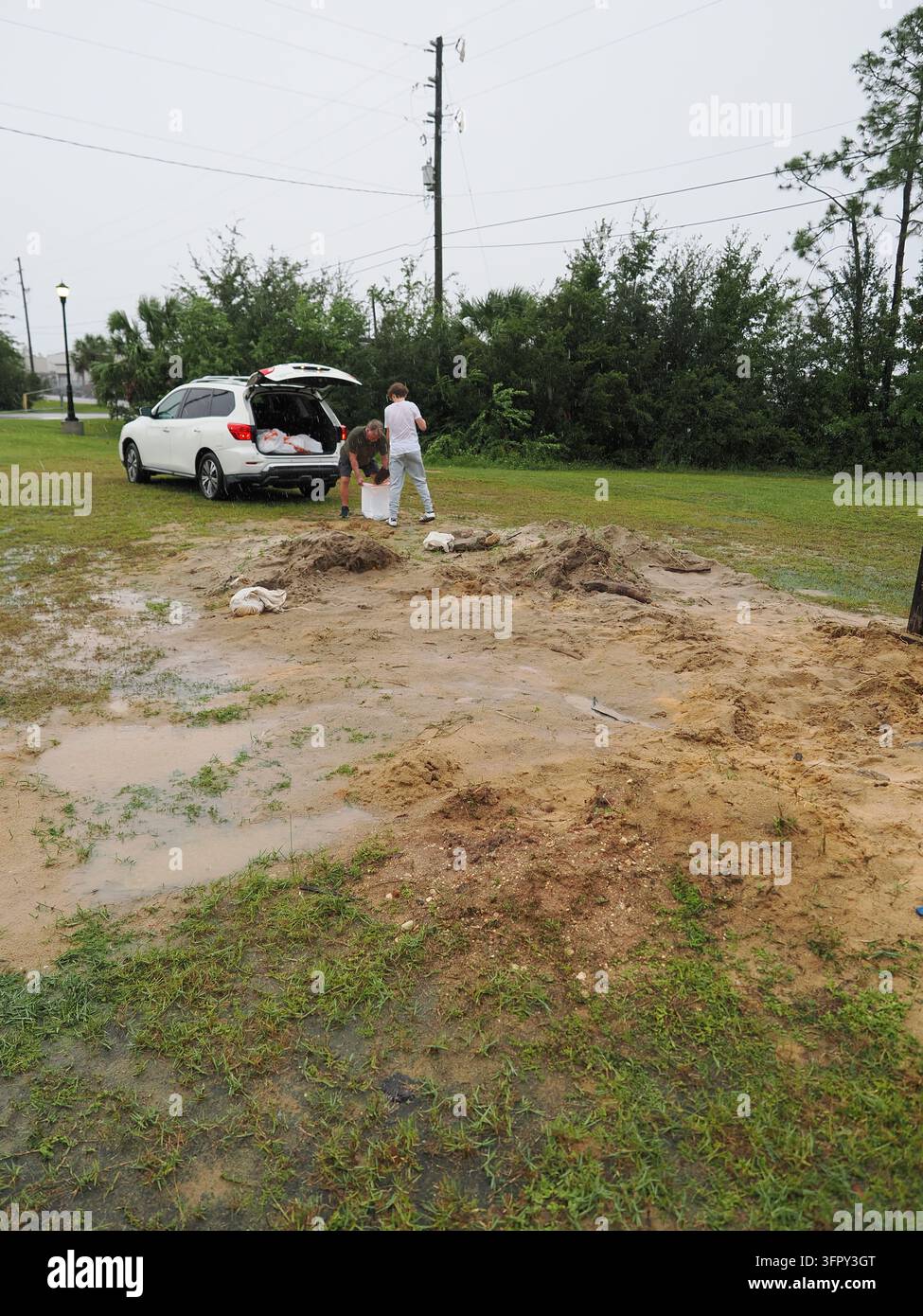 Panama City, FL, USA. 9 ott 2026. Un uomo e un adolescente riempiono l’ultimo dei loro sacchi di sabbia accanto a una pila di sabbia quasi esaurita e inzuppata dalla pioggia in un sito di distribuzione della città di Panama City mentre le bande esterne dell’uragano Isaias arrivano l’ultima mattina della distribuzione gratuita. La città ha detto ai residenti di completare i preparativi per la tempesta prima che le condizioni peggiorassero, con la contea di Bay sotto un avviso di uragano e di ondata di tempesta, da 1,2 a 2,1 metri di ondata previsti ed evacuazioni volontarie ordinate per le zone A e B. Credit: Tosh Persons / Alamy Live News Foto Stock