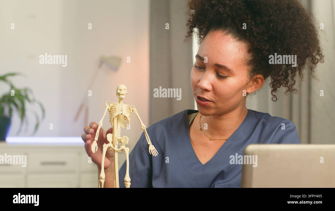 Il medico insegna anatomia con un modello in miniatura di scheletro durante l'educazione sanitaria Foto Stock