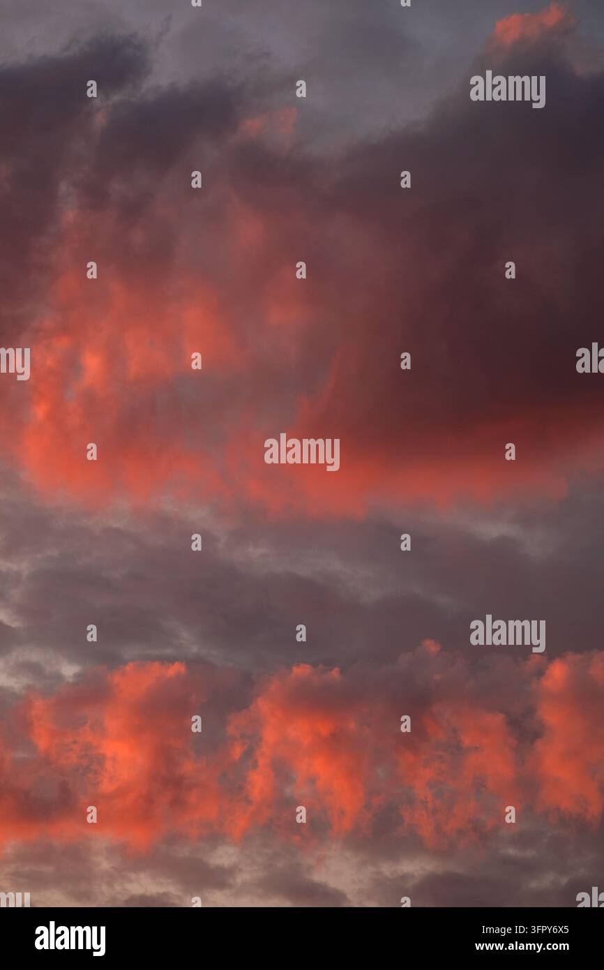 Cielo drammatico al tramonto con nuvole vibranti rosse e arancioni e atmosfera crepuscolare Foto Stock