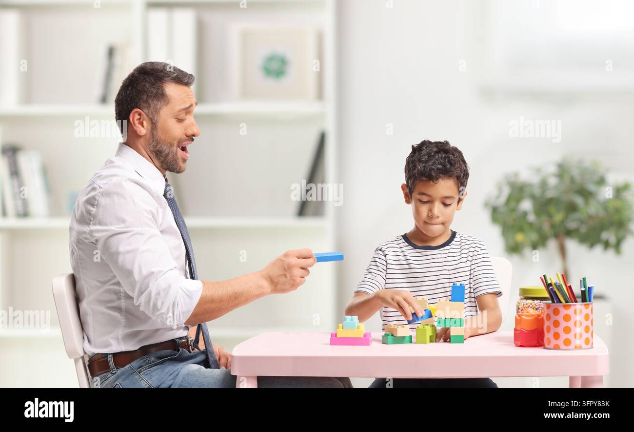 Padre che insegna al figlio a costruire con blocchi di plastica a casa Foto Stock