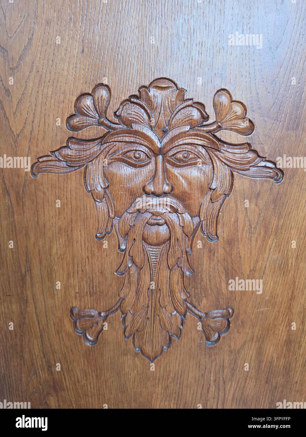 Decorazione a rilievo di volto di uomo verde in legno intagliato a mano con motivo fogliare su una superficie di porta in legno antico in Germania, primo piano. - Immagine stock catturata con smartphone