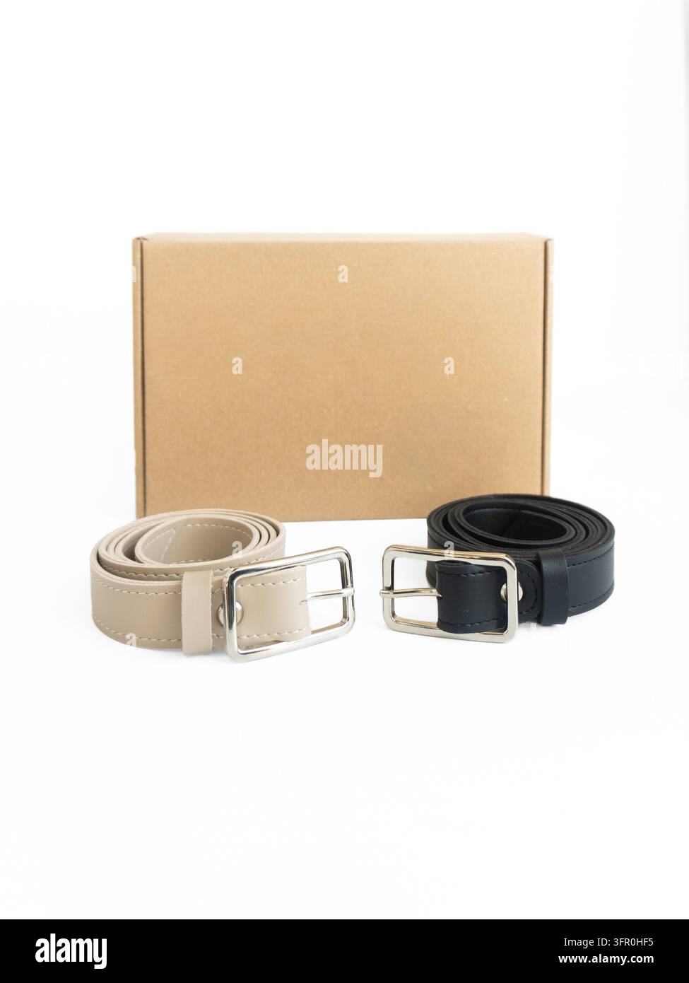Cinture in pelle nera e beige con fibbie argentate su sfondo bianco, mockup prodotto isolato. Foto di alta qualità Foto Stock