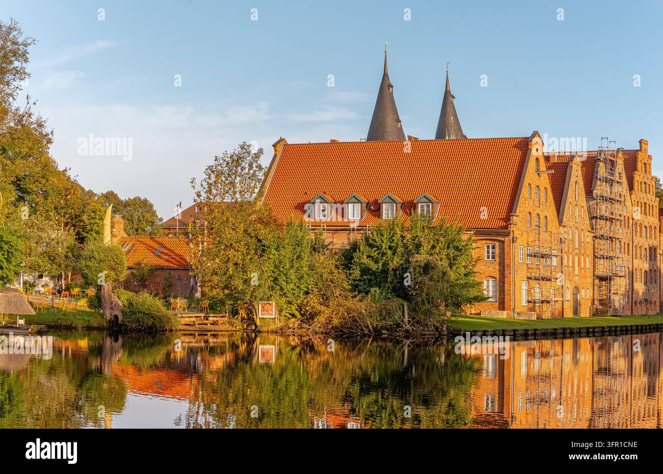 Magazzini di sale storici a Lubecca, Germania, con architettura gotica in mattoni rossi e luce calda della sera riflessa nel fiume Trave. Foto Stock