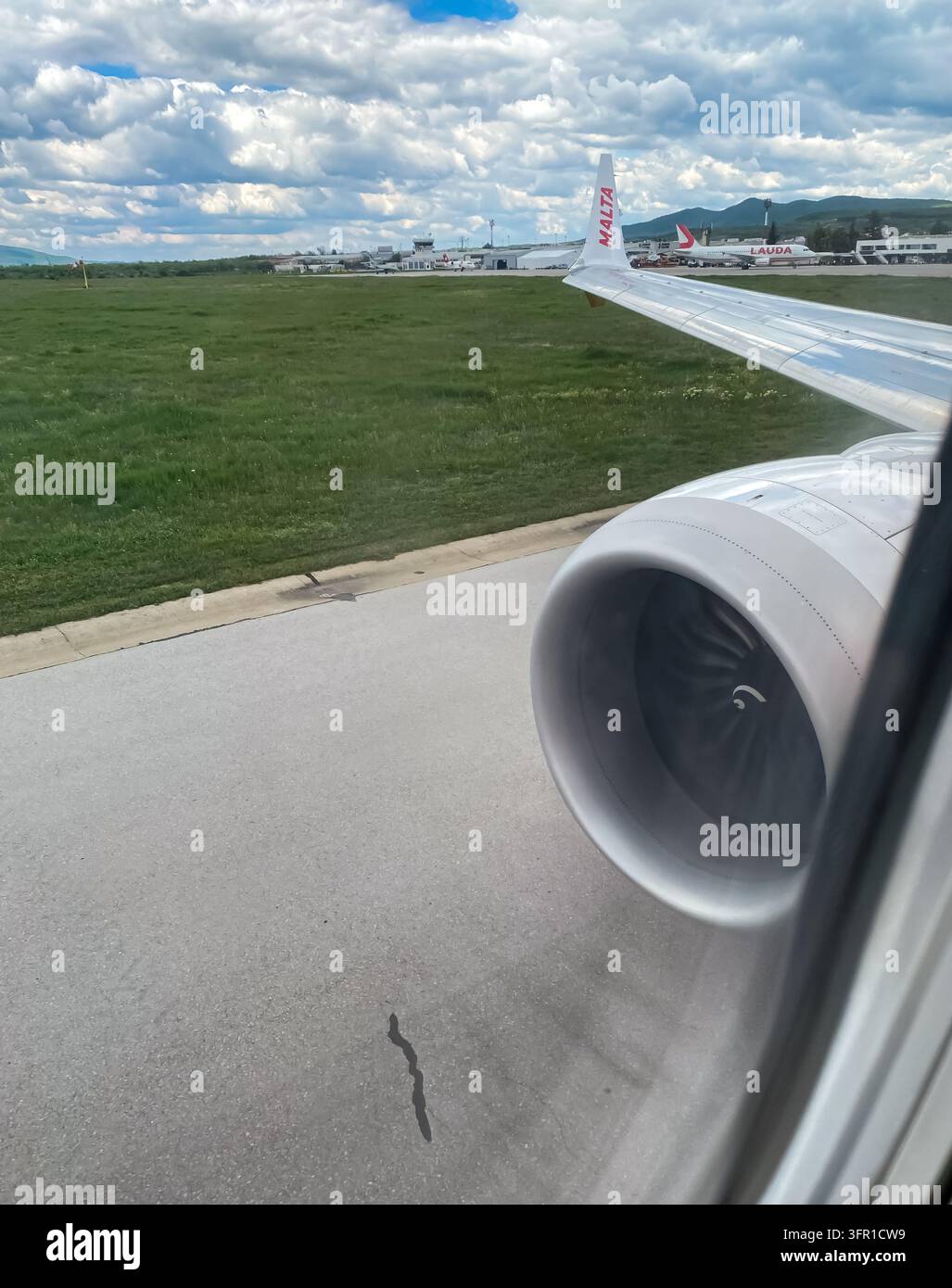 Vista attraverso il finestrino dell'aereo del motore e dell'ala di un jet di KM Malta Airlines sulla pista dell'aeroporto Foto Stock