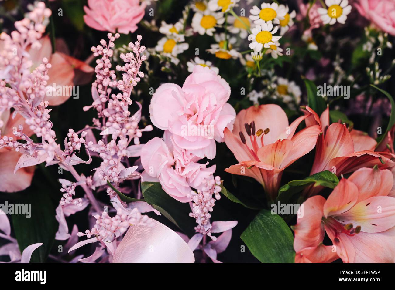 Arrangiamento floreale colorato con garofani rosa, gigli e piccole margherite bianche. Sfondo di bouquet di fiori per decorazione primaverile, fioristica. Foto Stock