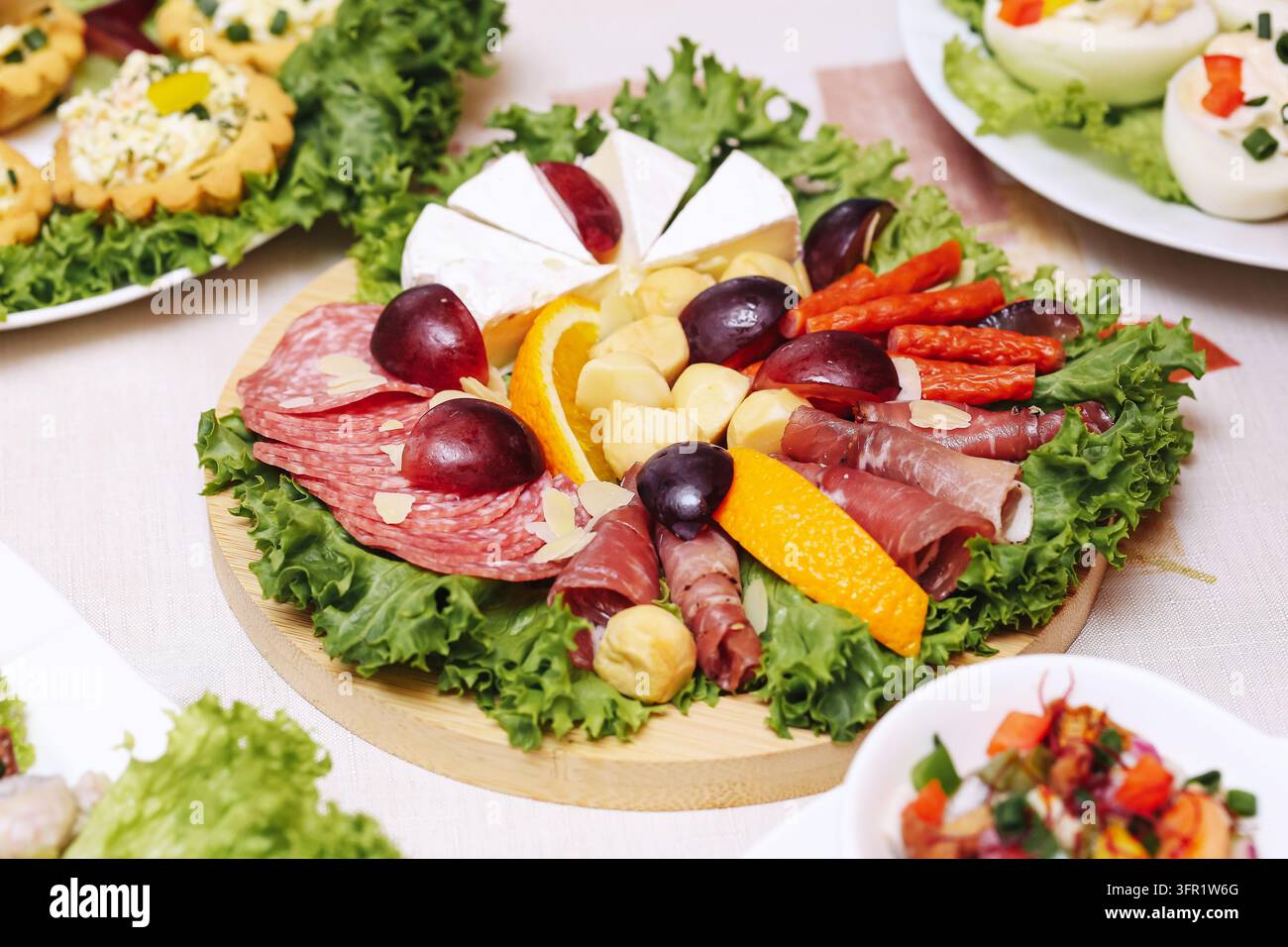 Piatto decorativo di salumi con salame, formaggio, uva e verdure fresche. Sfondo di cibo per feste per catering, antipasti e buffet festivo. Foto Stock