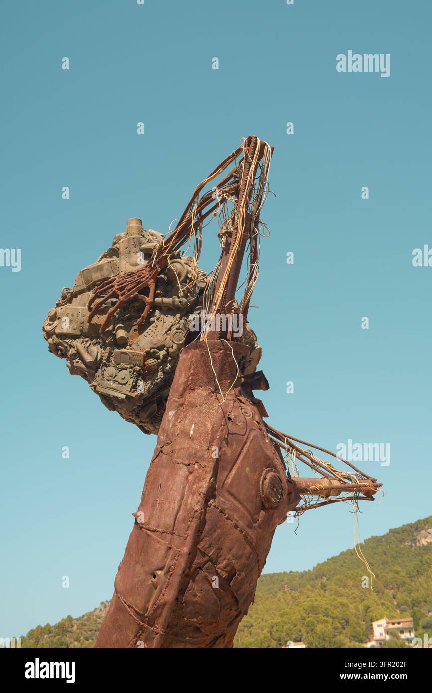 Primo piano di una scultura in stile industriale realizzata con metalli di scarto e vari componenti scartati, sullo sfondo di un cielo blu terso. L'opera d'arte presenta Foto Stock