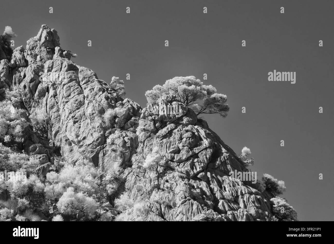 Una fotografia a infrarossi in bianco e nero cattura un paesaggio montano aspro a Maiorca, Spagna. Il soggetto principale è la parete rocciosa dalla trama netta wit Foto Stock