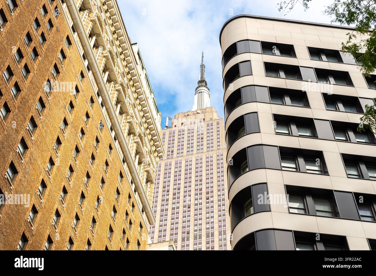 L'iconico Empire State Building visto tra due edifici contrastanti di Manhattan, che combina dettagli architettonici classici con un design moderno Foto Stock