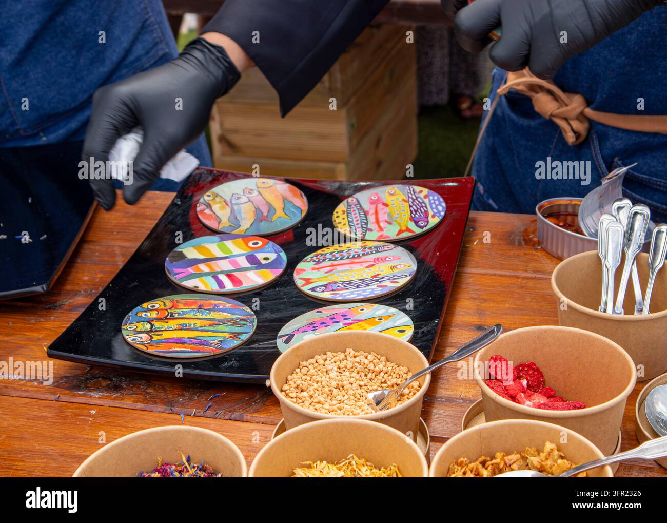 Chef che decorano piatti gourmet con arte colorata a base di pesce e condimenti croccanti Foto Stock