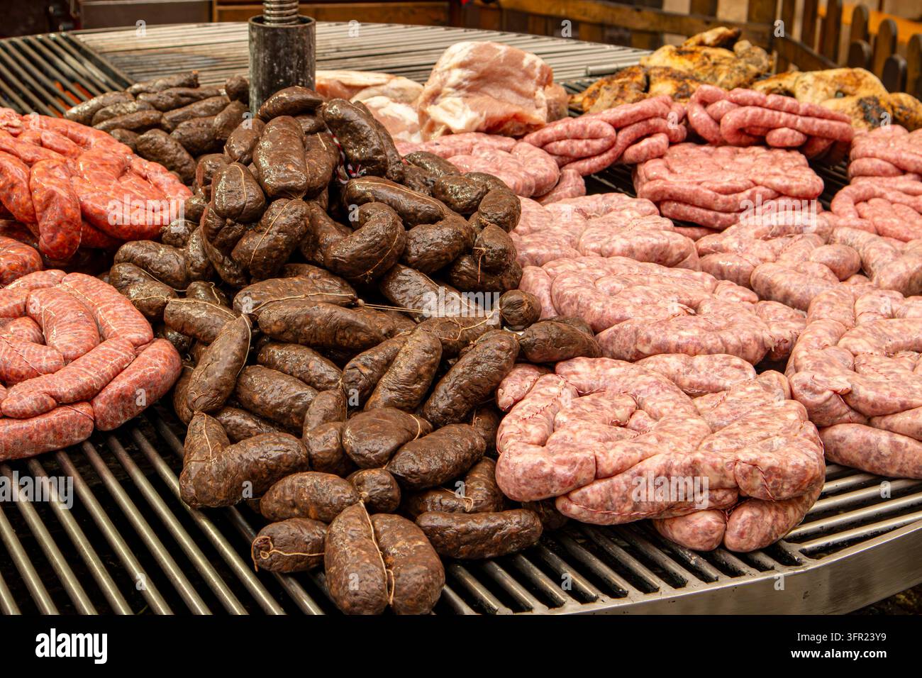 Varietà di salsicce crude fresche e sanguinaccio su griglia per barbecue Foto Stock
