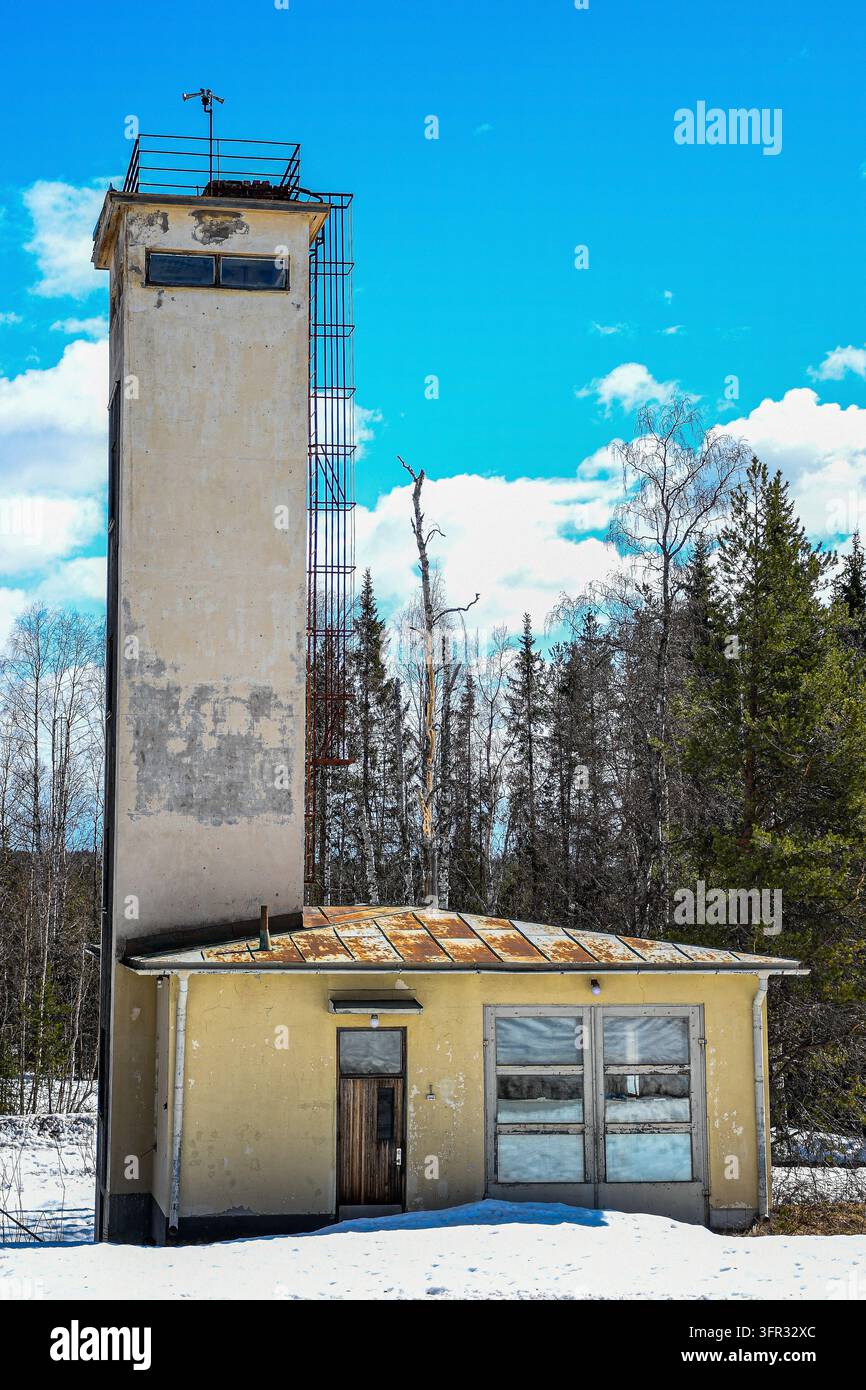 Ex stazione dei vigili del fuoco con un alto torre di asciugatura delle manichette a Murjek, comune di Jokkmokk, nella Svezia settentrionale, circondata da foresta e neve. Foto Stock