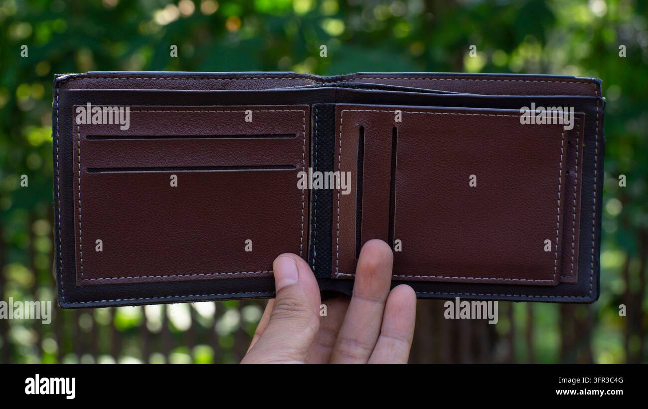 Mano che tiene un portafoglio marrone aperto all'aperto con spazio per il testo Foto Stock