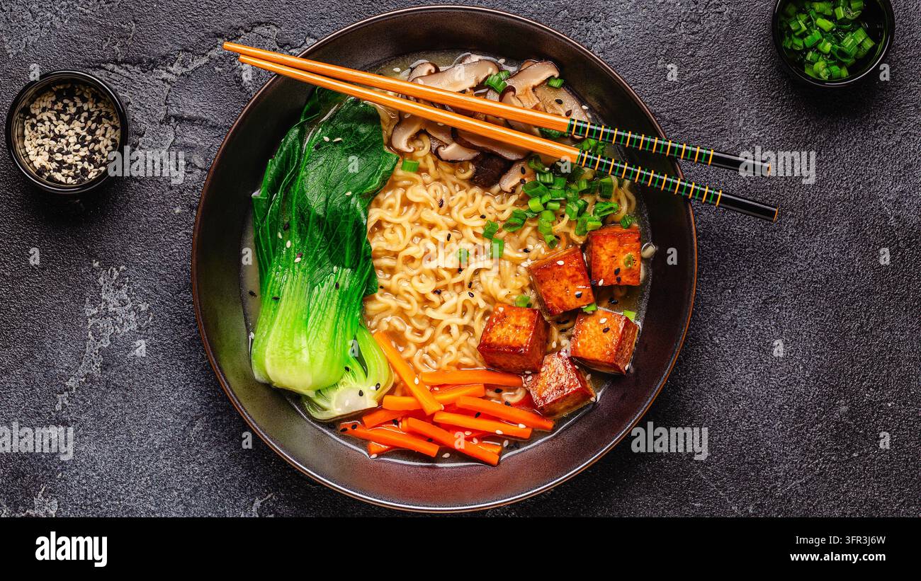 Zuppa miso ramen con noodles servita con tofu, bok choy, carote e funghi in una ciotola. Foto Stock