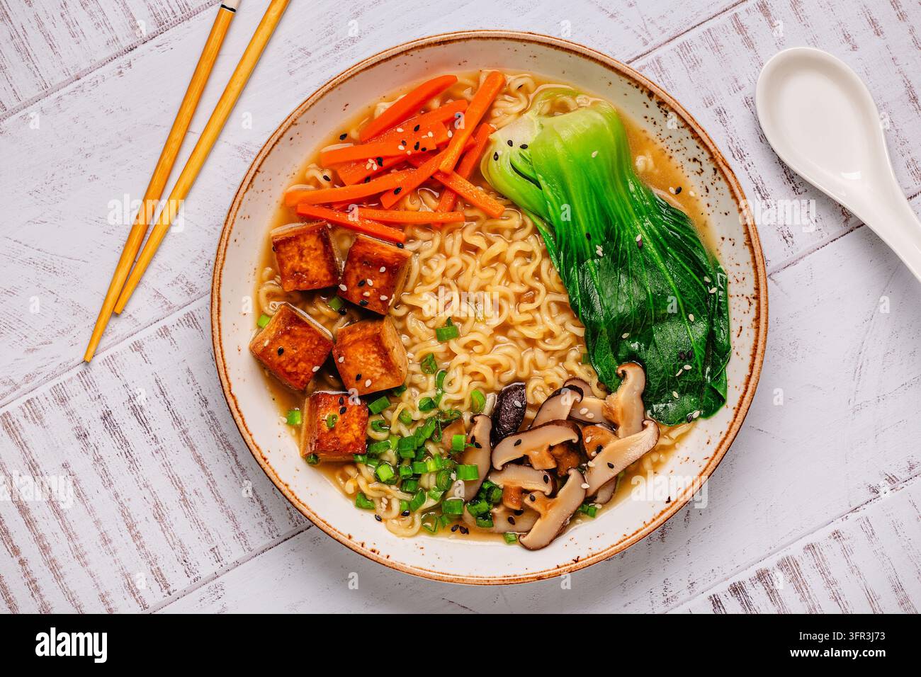 Zuppa miso ramen con noodles servita con tofu, bok choy, carote e funghi in una ciotola. Foto Stock