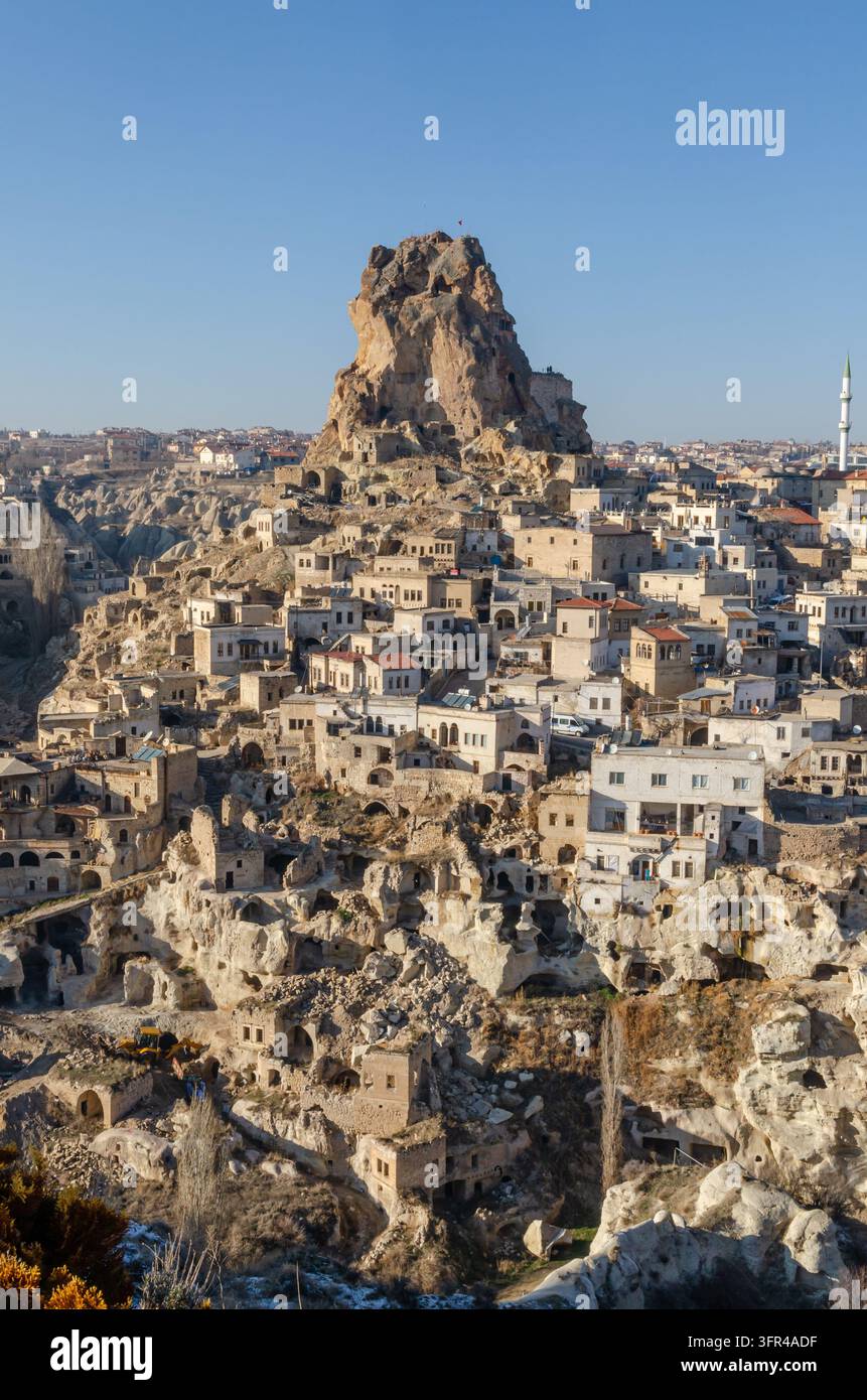 Il castello di Uçhisar si erge sopra l'insediamento storico scavato nella roccia di Uçhisar nella Cappadocia, Turchia, circondato da case tradizionali in pietra e abitazioni rupestri. Foto Stock