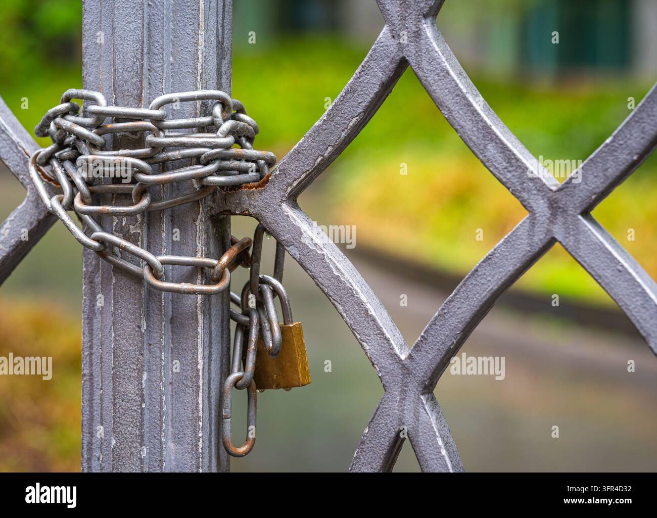 Cancello metallico chiuso fissato con una catena resistente e un lucchetto per la sicurezza Foto Stock