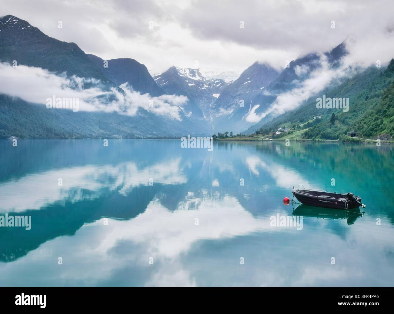 Una mattina nuvolosa e nebbiosa esalta la bellezza del lago Oldevatnet con le montagne che si riflettono nelle sue acque glaciali e il ghiacciaio Briksdalsbreen visibile Foto Stock