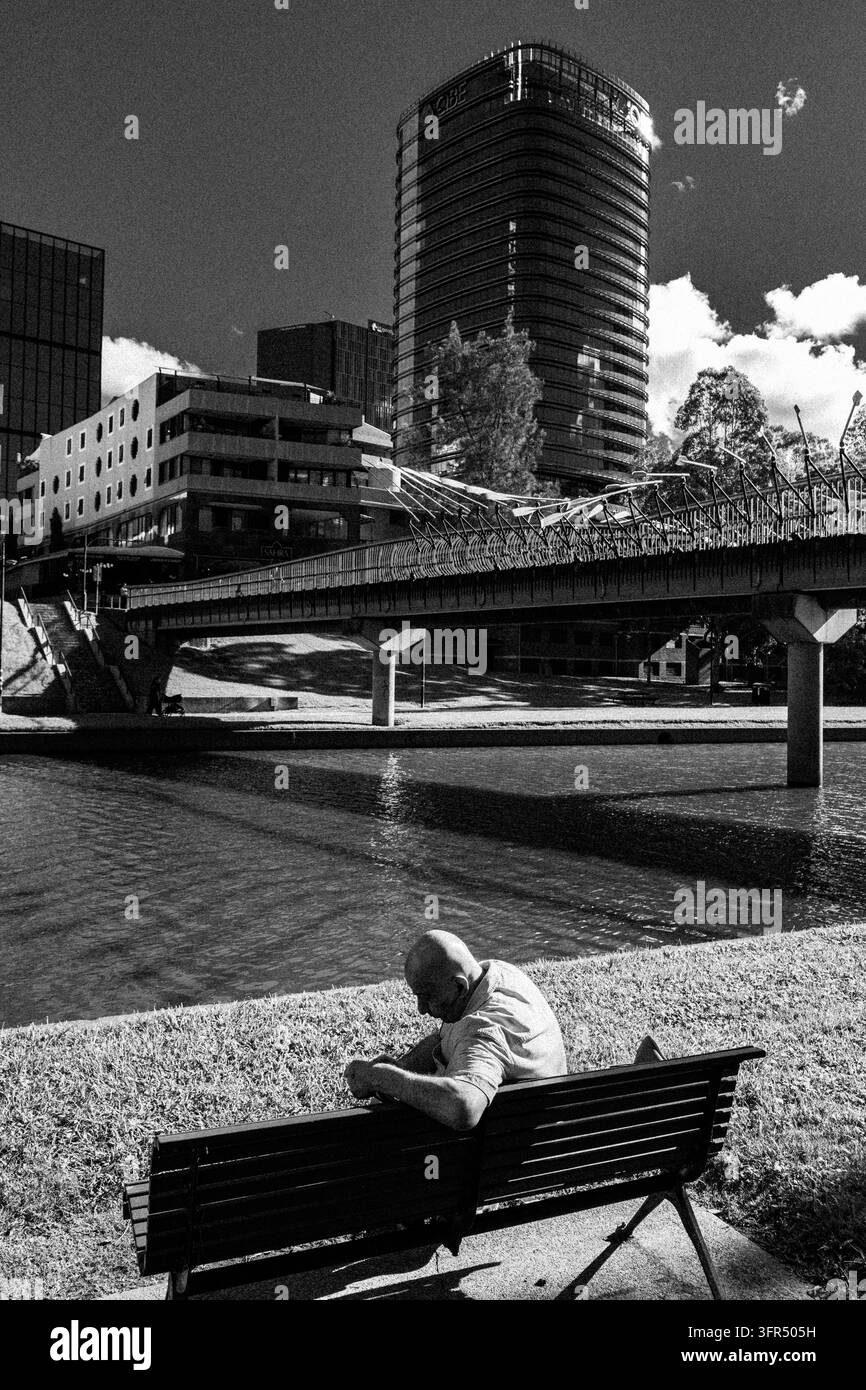 Un uomo anziano siede solo accanto al fiume Parramatta Foto Stock
