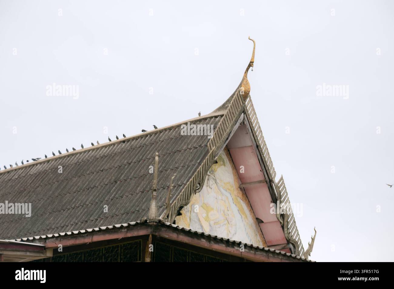 Architettura tradizionale del tetto del tempio asiatico con dettagli ornamentali e uccelli seduti in cima Foto Stock